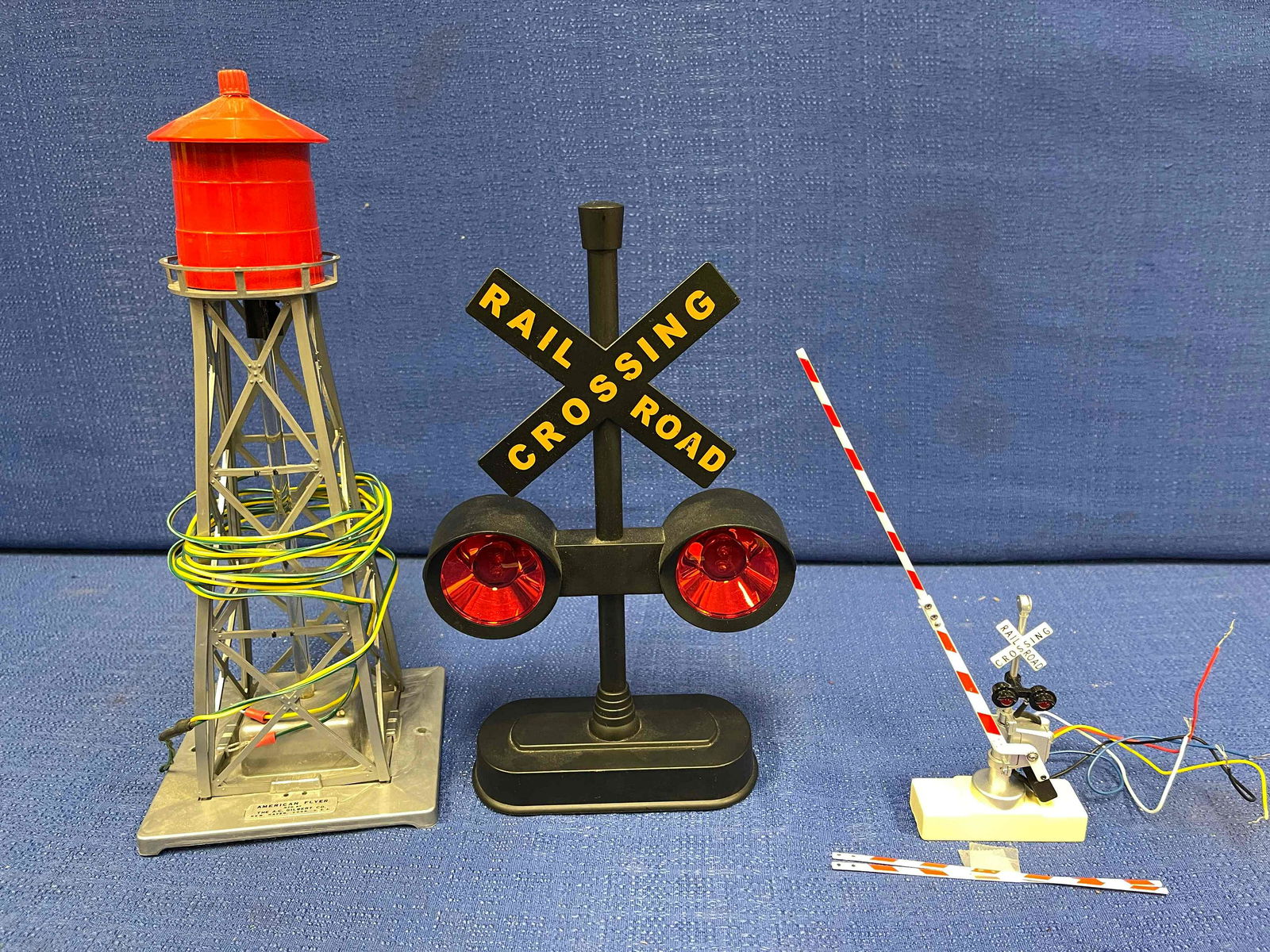 2 O scale Crossing Signals; 1 O scale Water Tower: One American Flyer (Mfg. by the A.C. Gilbert Co.) Lighted Water Tower; One powered R.R. crossing arm - metal with two extra arms; One plastic battery-operated R.R. crossing light with sound.