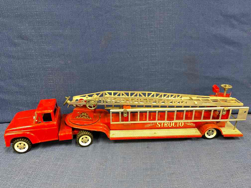 Vintage Structo Toy Firetruck, Hook, and Ladder: Structo Toys. Has the windshield wipers. Mirrors are missing. May have had a top light at one time. Tin is very straight. Minor paint blemishes.