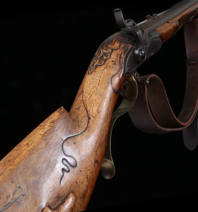 Circa 1840 large calibre carbine rifle, with percussion: Circa 1840 large calibre carbine rifle, with percussion sidelock, wavy brass trigger guard, slide compartment to the walnut stock, unsigned 45cm long barrel with ram rod below, overall length 82cm - S