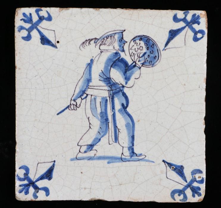 17th century blue and white tile, decorated with a: 17th century blue and white tile, decorated with a figure holding a warming pan, 13cm square