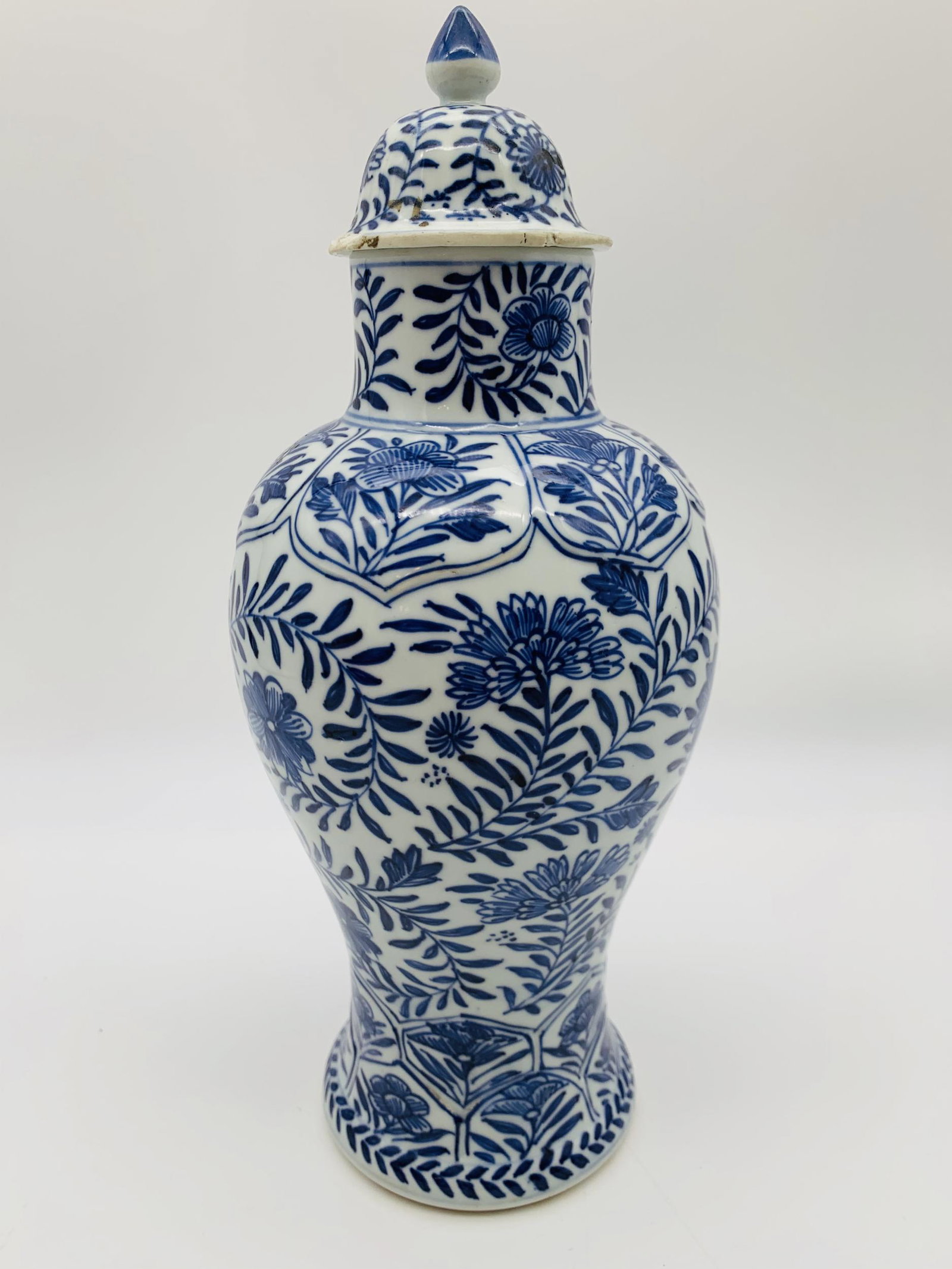 Chinese Kangxi Blue & White Covered Vase. Decorated: Chinese Kangxi Blue & White Covered Vase. Decorated with a continuous floral motif on both vase and lid. Raised lotus leaf border at top and bottom of vase, Old firing crack on bottom. Minor flea bite
