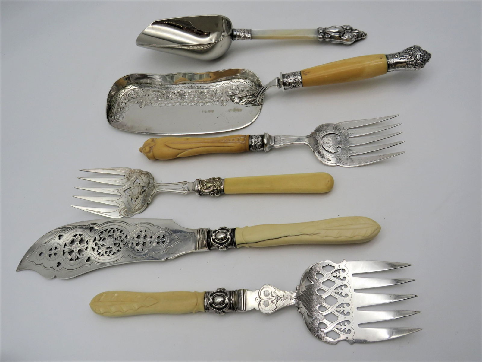 6 Victorian Silver Plate Serving Utensils: 6 Victorian Silver Plate Serving Utensils. Each piece very decorative and ornate, 5 with bone handles, the scoop with MOP handle. The lot includes: crumber 13-1/4" L; fish set, 2 meat forks, the scoop