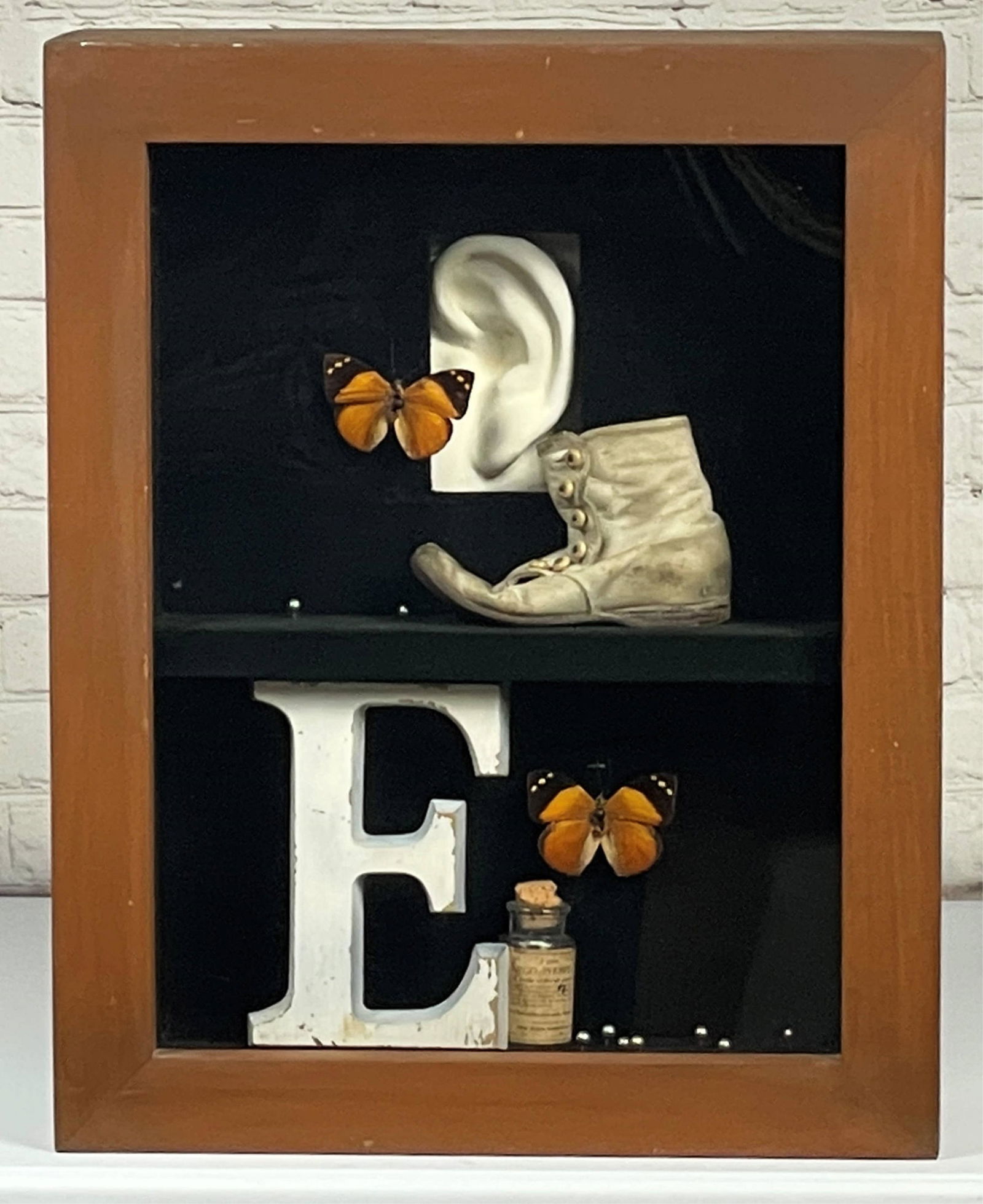 Leo Kaplan Mixed Media Assemblage "E is for Ear, 1983": Leo Kaplan (American 1912-2012) Mixed Media Assemblage "E is for Ear, 1983". Similar in style to artist Joseph Cornell (American 1903-1972). In shadowbox. Inscribed in marker, Gallery Tags verso. Good