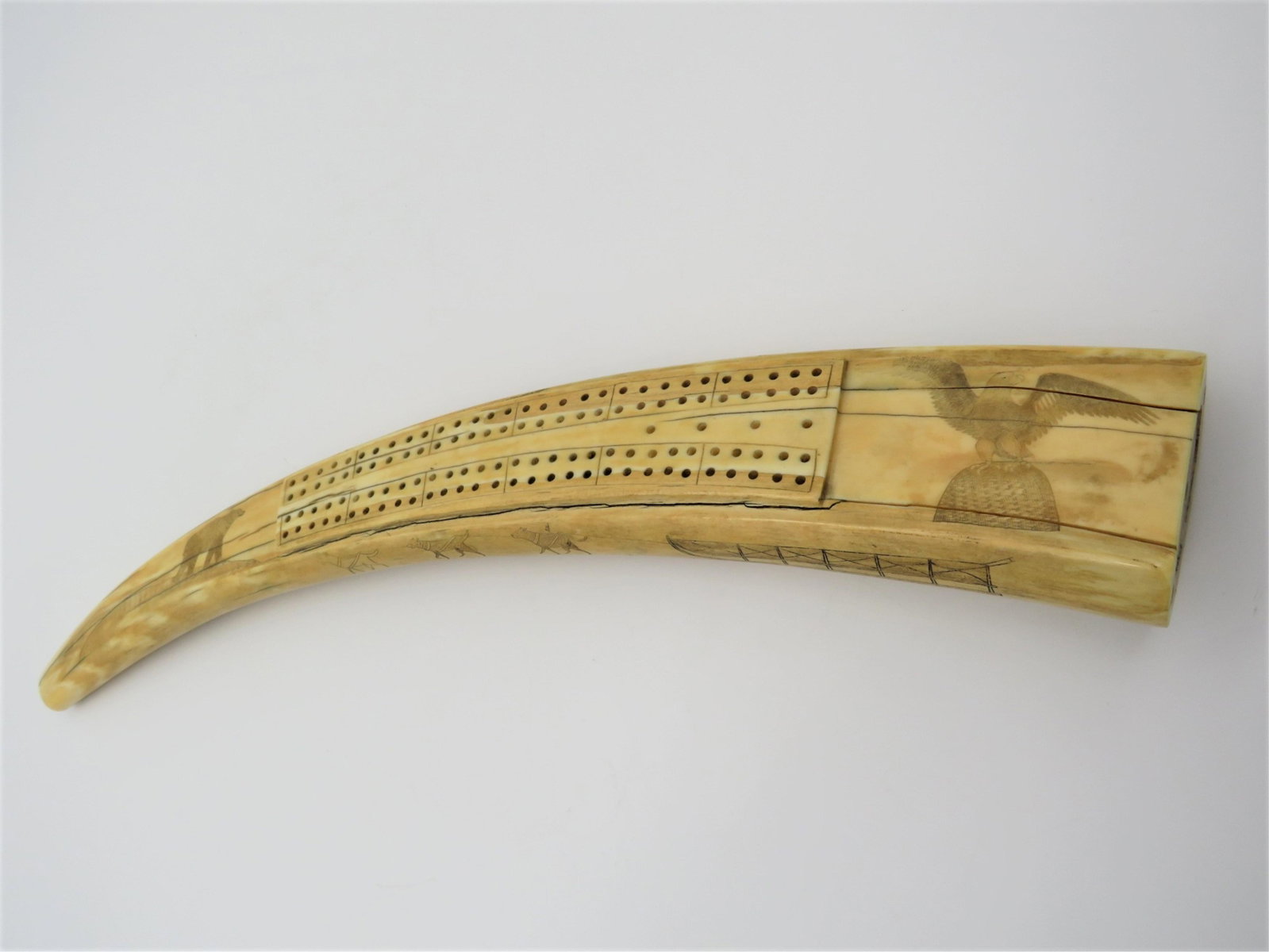19C Walrus Scrimshaw Cribbage Board: 19th Century Walrus Scrimshaw Cribbage Board. Detailed scrimshaw featuring eagle, bear, sleds with dogs and reindeer, walruses. Good period condition. Unsigned. Measures 17-1/4" L x 2-3/4" at widest x