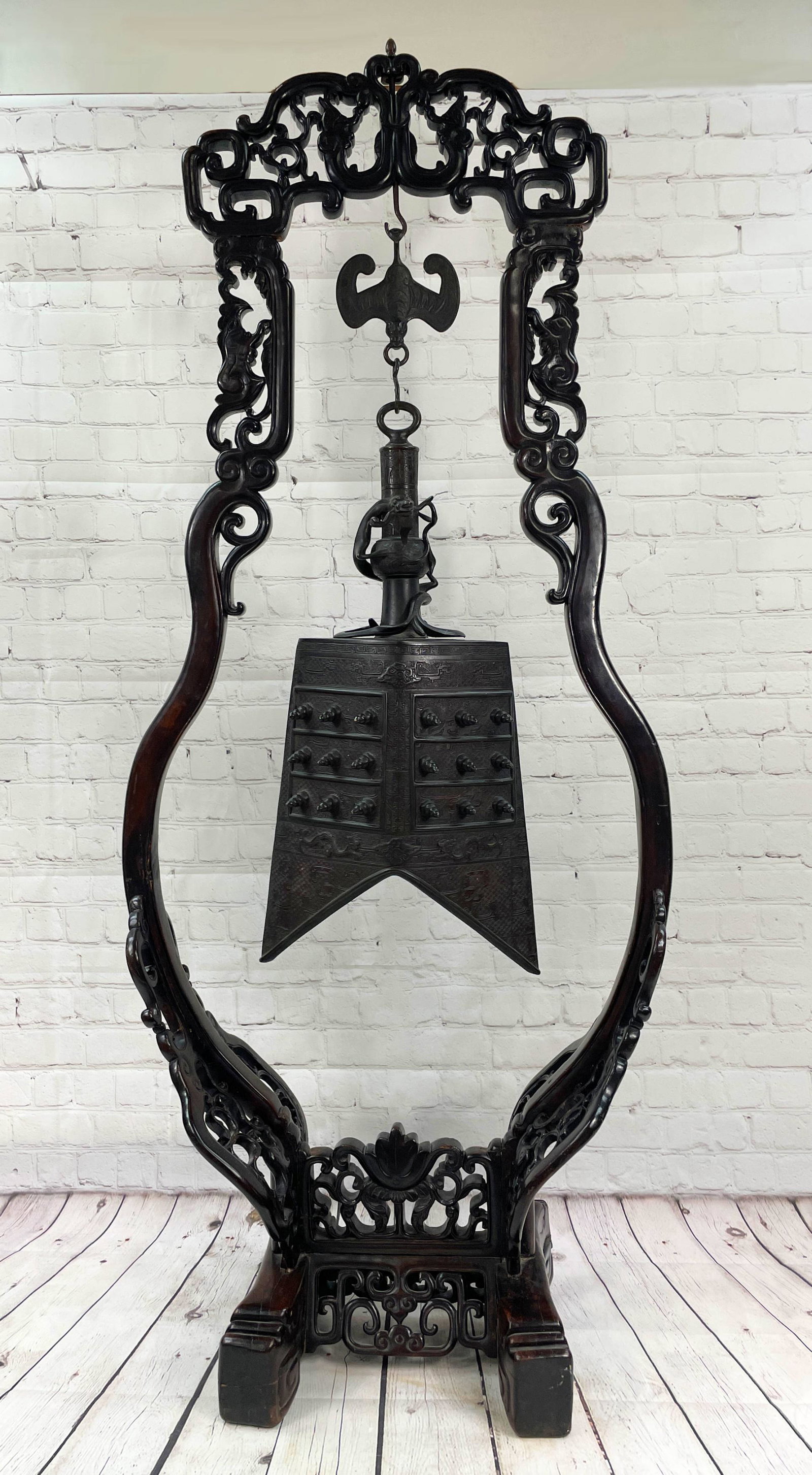 Standing Chinese Bronze Chime Bell On Stand Standing: Standing Ornate Chinese Bronze Chime Bell on Carved Ebonized Wood, Possibly Zitan Stand. The ornate temple size bronze bell suspended by a bat, the stand carved throughout. Possibly Imperial. Unsigned