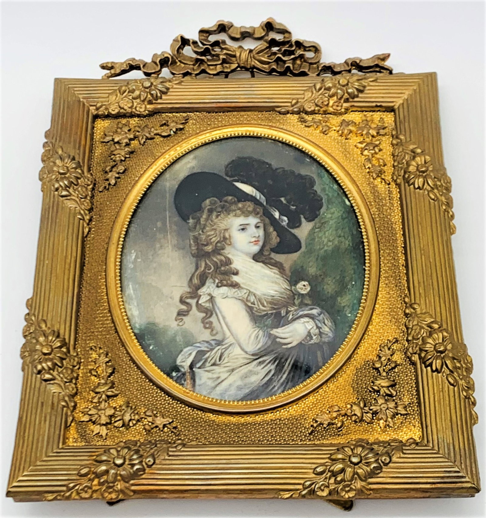 19C Hand Painted Portrait In Gilt Bronze Frame: 19th Century Hand Painted Porcelain Portrait In Gilt Bronze Frame. Well painted portrait of a woman in period costume. The oval porcelain in ornate gilt bronze frame. Unsigned. There is wear and a rep