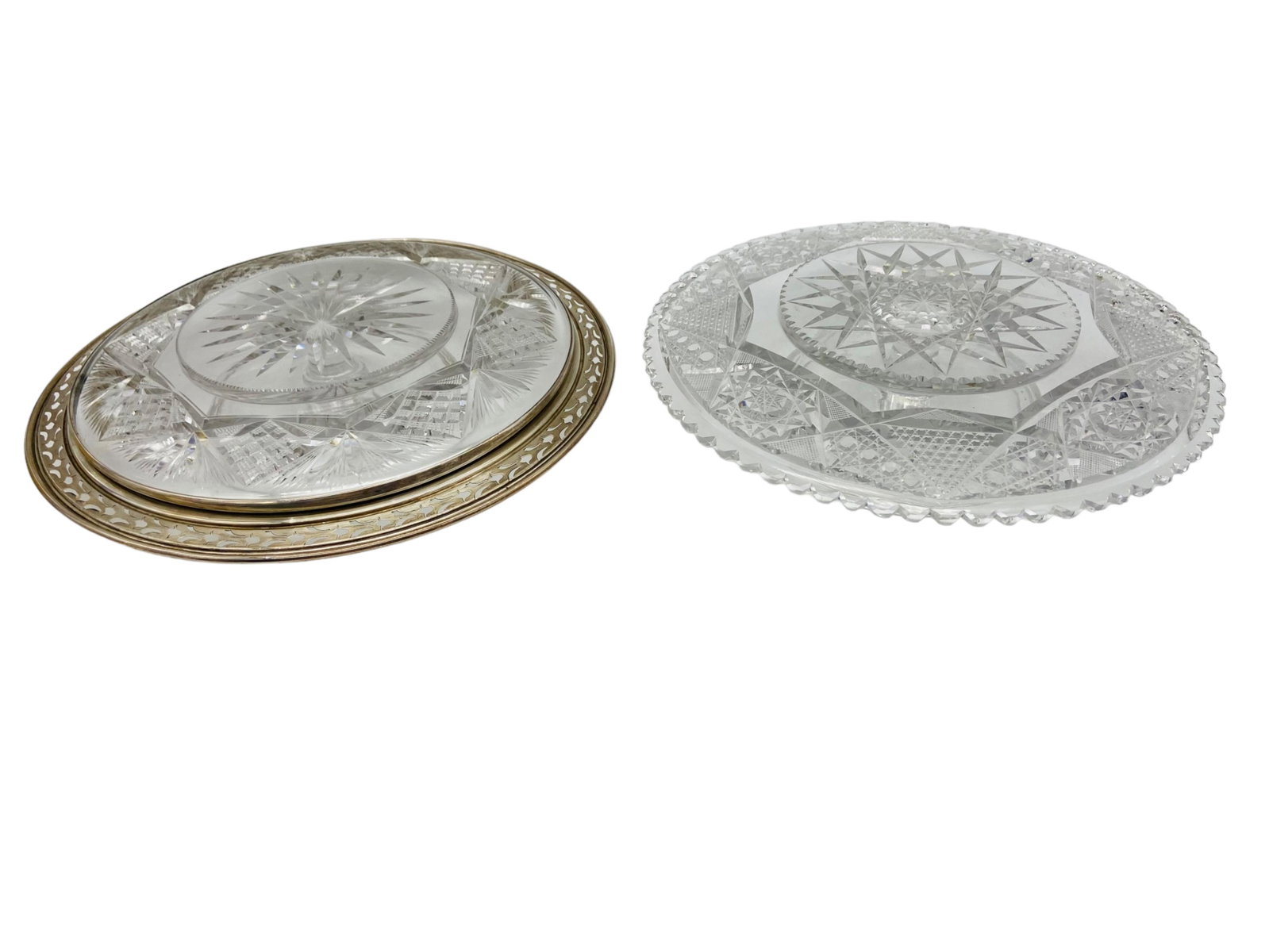 Two Cut Glass Cake Stands With Sterling Silver Rim: Two cut glass cake stands, one with a sterling silver rim, marked. Glass is unmarked. Measures 2.5", 3" H x 10 1/4", 9.5" D. In good condition,, some chipping to teeth and scratches to both stands, si
