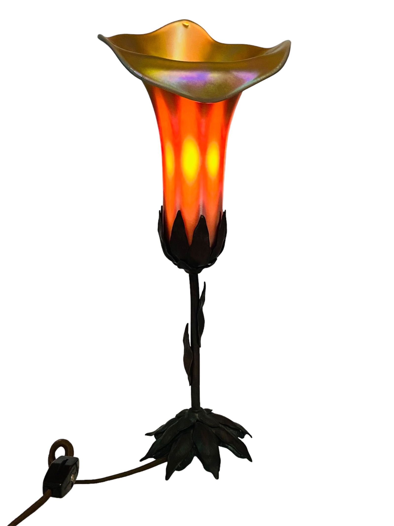 John Cook Phoenix Studios Art Glass Lamp: John Cook Phoenix Studios Art Glass Lamp. Flower petal shape shade with iridescent colors and a ruffled rim, stem motif base. Signed on bottom. Measures 14.5" H x 6" D. In excellent condition, no chip
