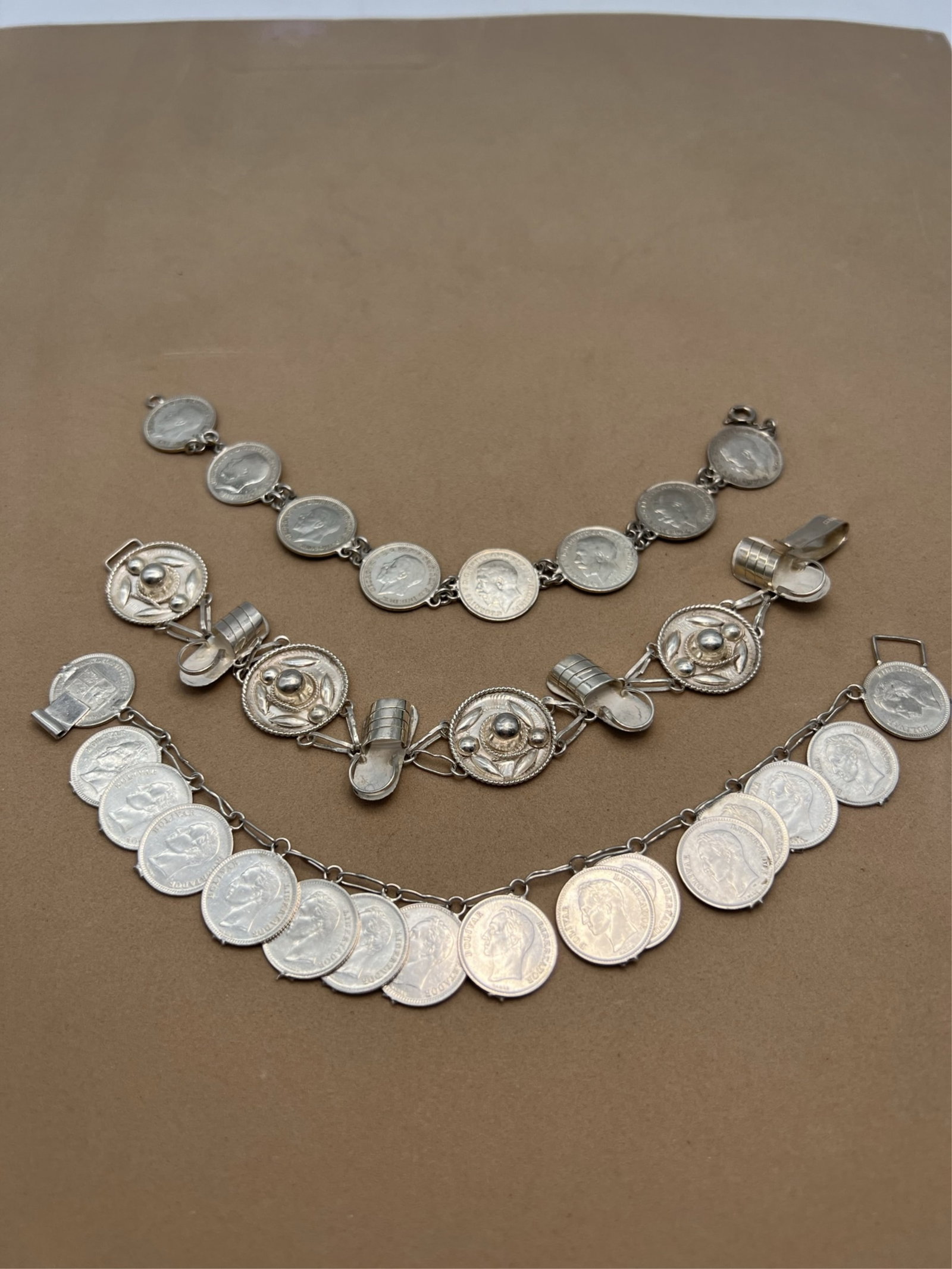 3 Vintage Silver Coin & Novelty Bracelets: 3 Vintage Silver Souvenir Novelty Bracelets. Lot includes: a George V coin bracelet with coins dating from 1911-1934; au undated Venezuelan coin bracelet and a Mexican souvenir bracelet. All are silve