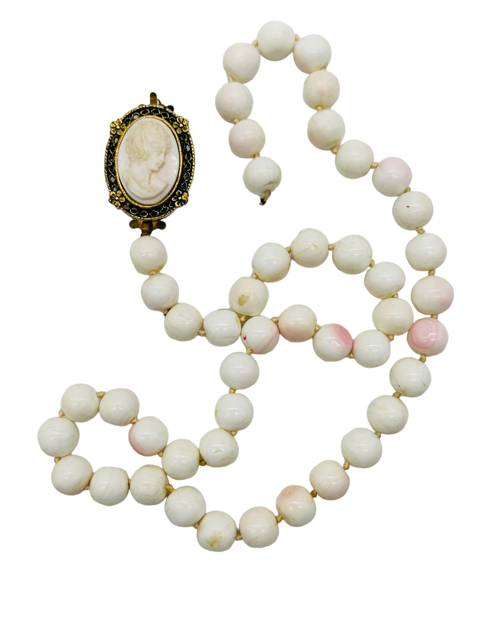 White & Pink Coral Cameo Beaded Necklace: White & Pink Coral Cameo Beaded Necklace. 12mm white and pink coral beads with a carved coral cameo set in gold tone filigree mount. Unmaked. The cameo has come loose from the strand on one side or in
