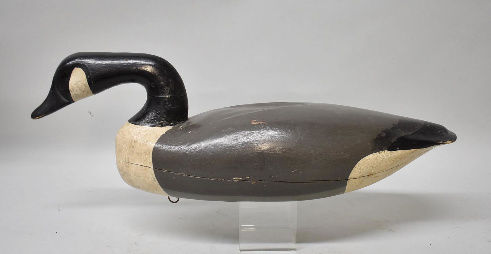 Vintage Goose Decoy: Vintage goose gunning model decoy with minor paint wear, old neck repair, age crack along midline, leather straps and metal ring for tie line on bottom. Dimensions 22 1/2" long x 7 1/4" tall x 6 1/4"