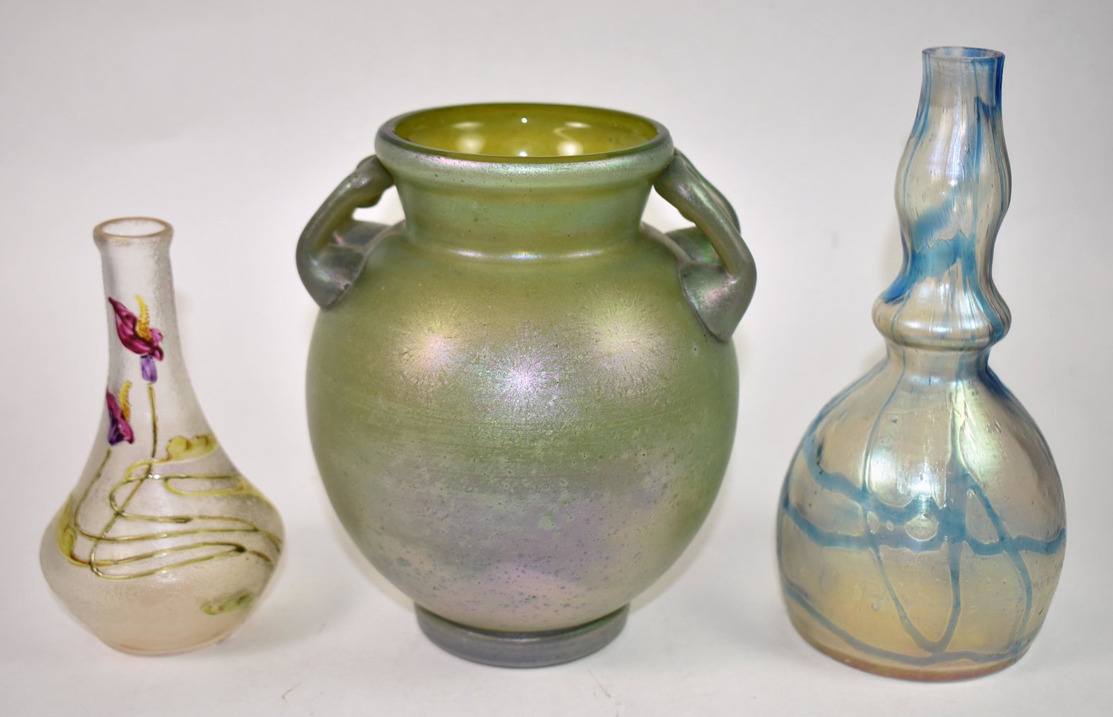 3 Pieces European Art Glass: 3 Pieces European art glass. 7 1/2" x 3 1/2" Barber bottle Loetz style. Green iridized finish 6 1/2" x 5 1/2" diameter vase with 2 handles with painted flowers. Bud vase cameo cut enamel work, calla l