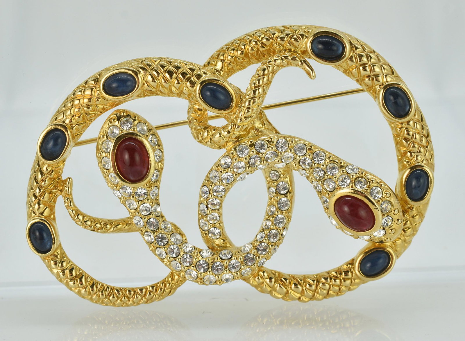 Kenneth J Lane Snake Brooch for Avon: Kenneth J Lane snake brooch pin for Avon. Two intertwined snakes with red and blue cabochon, and crystals for a pretzel shape. 3" long x 2" wide. 35.8 grams.