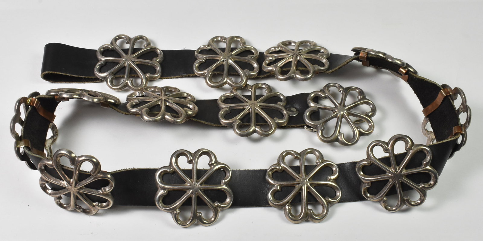 Sterling Cast Sunflower Conch Belt: Sterling cast sunflower conch belt. Marked Sterling 925 with Navajo Arts and Crafts Guild hallmark. No maker's name. 36" long. 385.8 grams with leather. Buckle 1 3/4" wide x 1 1/2" long. 13 conchos 1 