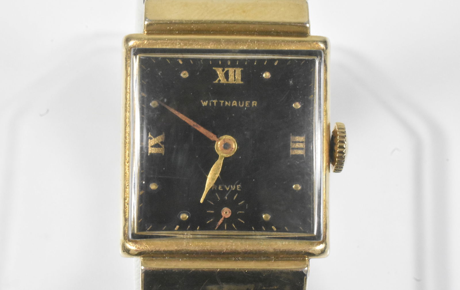 Wittnauer Mens Tank Wristwatch: Wittnauer tank watch with 10k GF case, black dial and unique band with calendar. 17 jewel movement, running. Case marked Longines - Wittnauer. Some wear to the dial and scratches on the crystal.