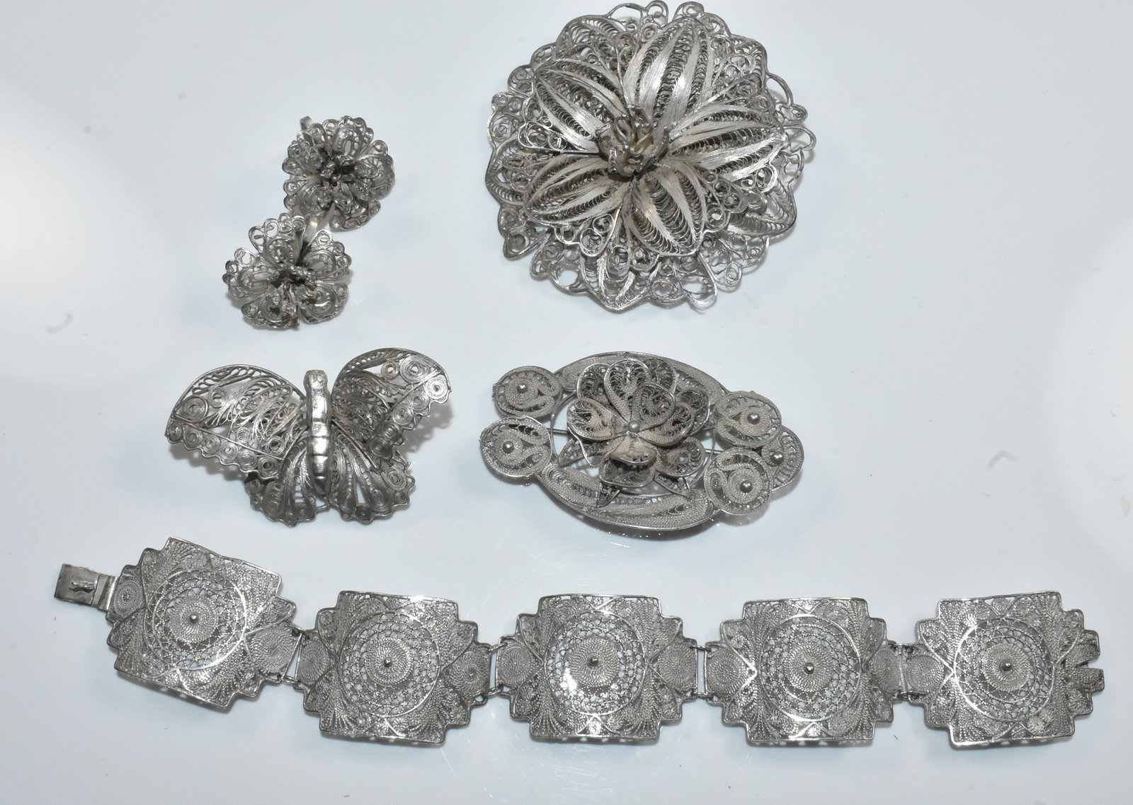 Silver Filigree Jewelry Group: Group of silver filigree ladies jewelry includes large flower pin brooch 2 3/4" wide; oval pin brooch 2 3/8" wide; butterfly pin brooch 2 1/4" wide; earrings with screw backs 1" wide; bracelet 7" x 1"