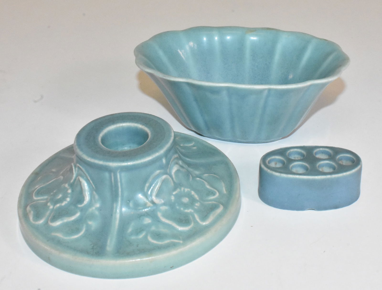 3 Rookwood Pieces with Bowl and Candle Holder: 3 Rookwood pieces in blue. Flared bowl, 1929, with a flower frog, interior stains. Candle holder #2473, 1920, with a floral design, 5" wide.
