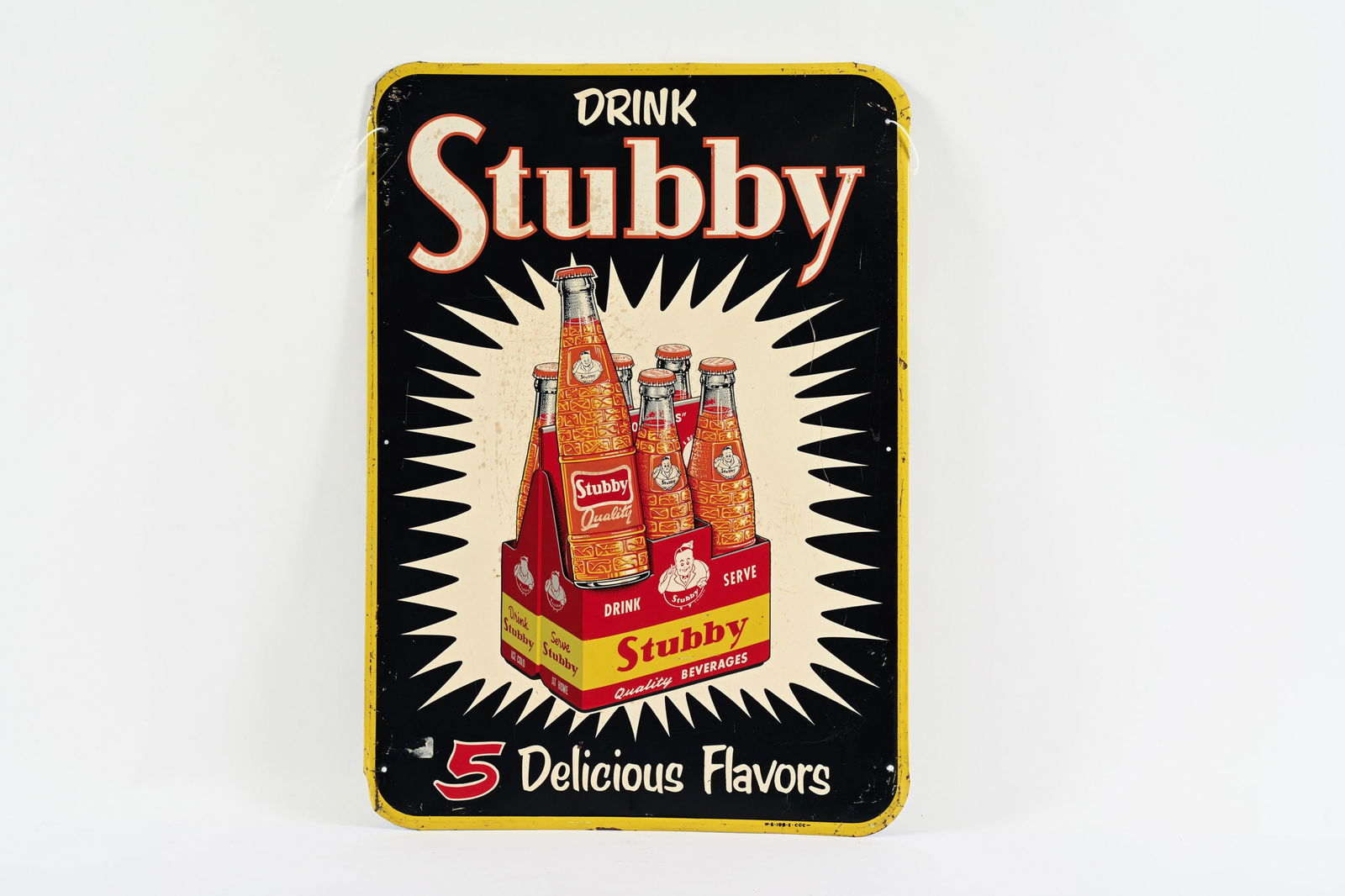 DRINK STUBBY "5 DELICIOUS FLAVORS" EMB.TIN 6-PACK SIGN: DRINK STUBBY "5 DELICIOUS FLAVORS" EMBOSSED TIN 6-PACK SIGN MARKED W-S-196-E- CCC SELF FRAMED EDGE GREAT GRAPHIC WITH GOOD COLOURS AND GLOSS SHOWS SOME STAINING AND SURFACE STRACTCHES IN FIELD 