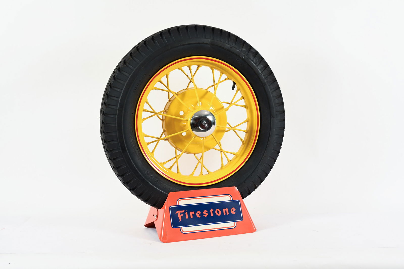 FIRESTONE TIRE WITH SPOKED RIM ON TIRE STAND: FIRESTONE TIRE WITH SPOKED RIM ON TIRE STAND TIRE IN NEW OLD STOCK CONDITION TIRE SIZE 4.75/5.00-19 RESTORED RIM WITH FORD CHROME HUB CAP WITH FIRESTONE TIN TIRE STAND