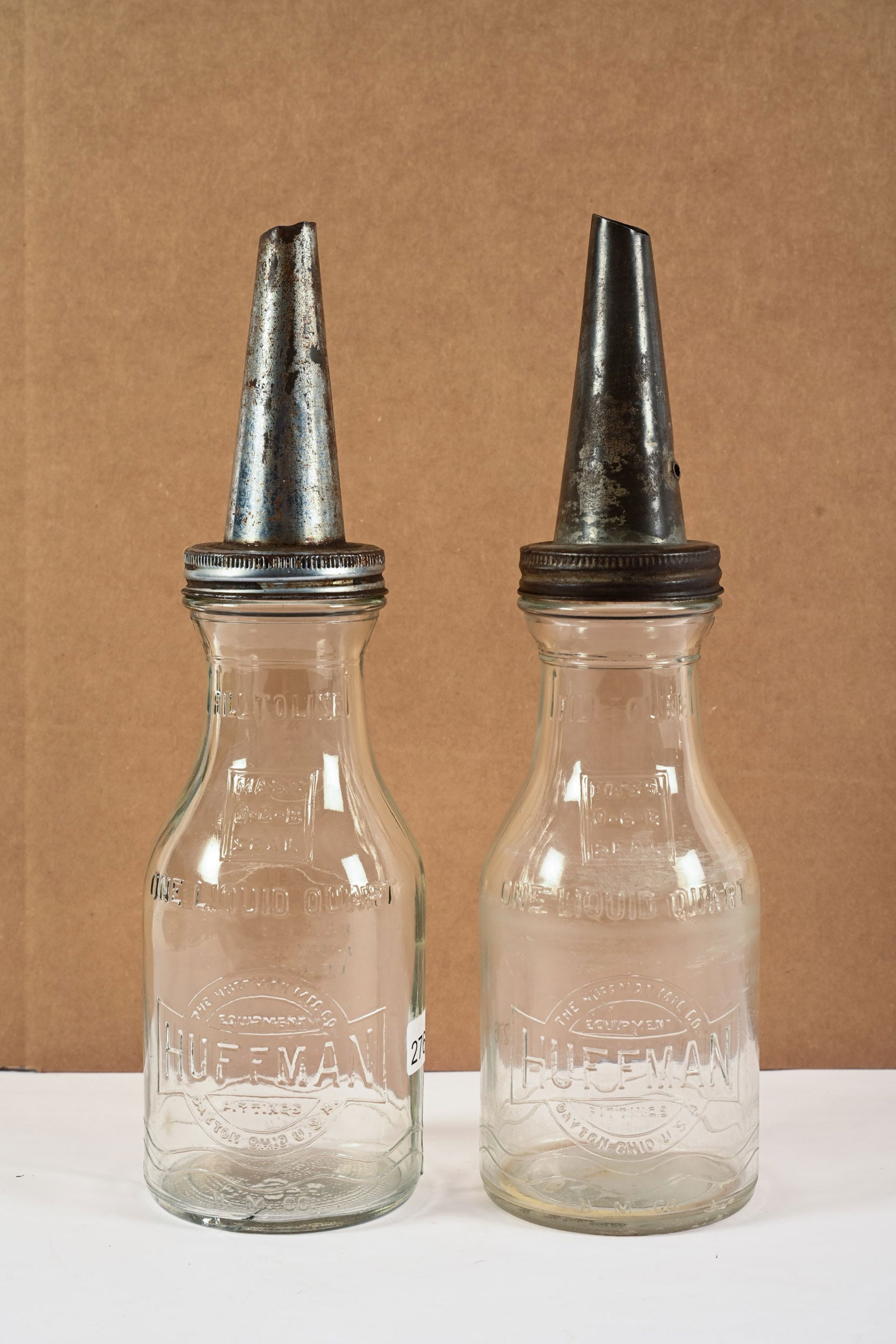 PAIR OF HUFFMAN GLASS QT MOTOR OIL BOTTLES W/SPOUTS: PAIR OF HUFFMAN GLASS QUART MOTOR OIL BOTTLES WITH SPOUTS HUFFMAN MFG, CO. DAYTON, OHIO EMBOSSED GLASS NO CHIPS OR CRACKS SOME INNER STAINING ON ONE BOTTLE