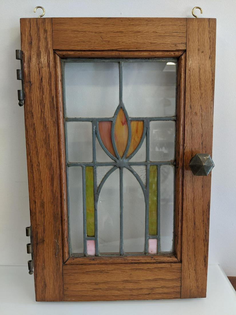 Pair of stained glass windows: Sweet pair of leaded antique stained glass panels, arts and crafts. measuring 16 1/8" tall x 10 1/2"each weighing 4 lbs. Oak frame and original cabinet hardware still in place. One small hairline crac