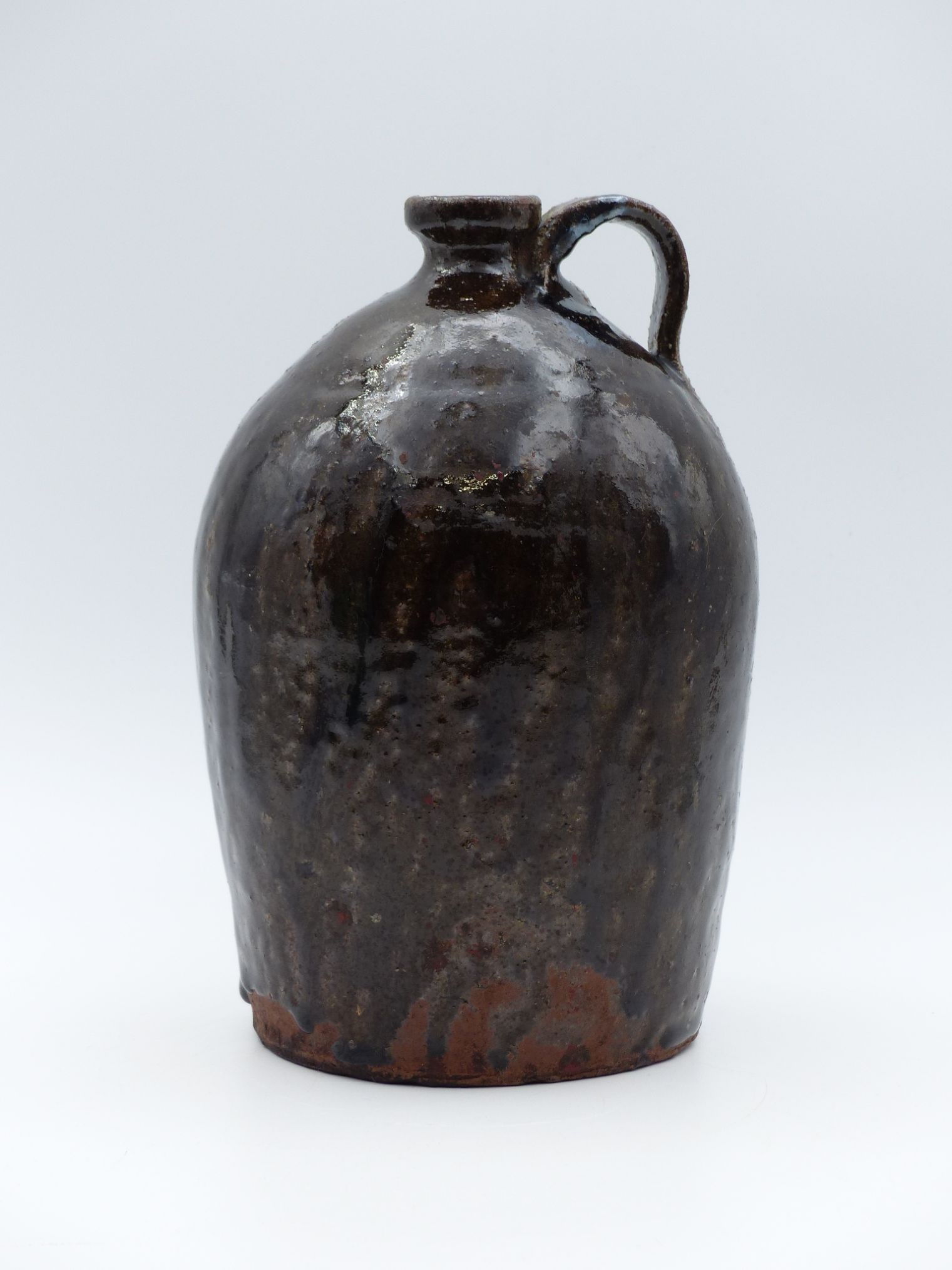 "Catawba Valley Alkaline Glaze Jug: This remarkable Catawba Valley Alkaline Glaze Jug showcases the craftsmanship of traditional American stoneware. Characterized by its rich, mottled glaze in deep browns, the jug features a distinctive