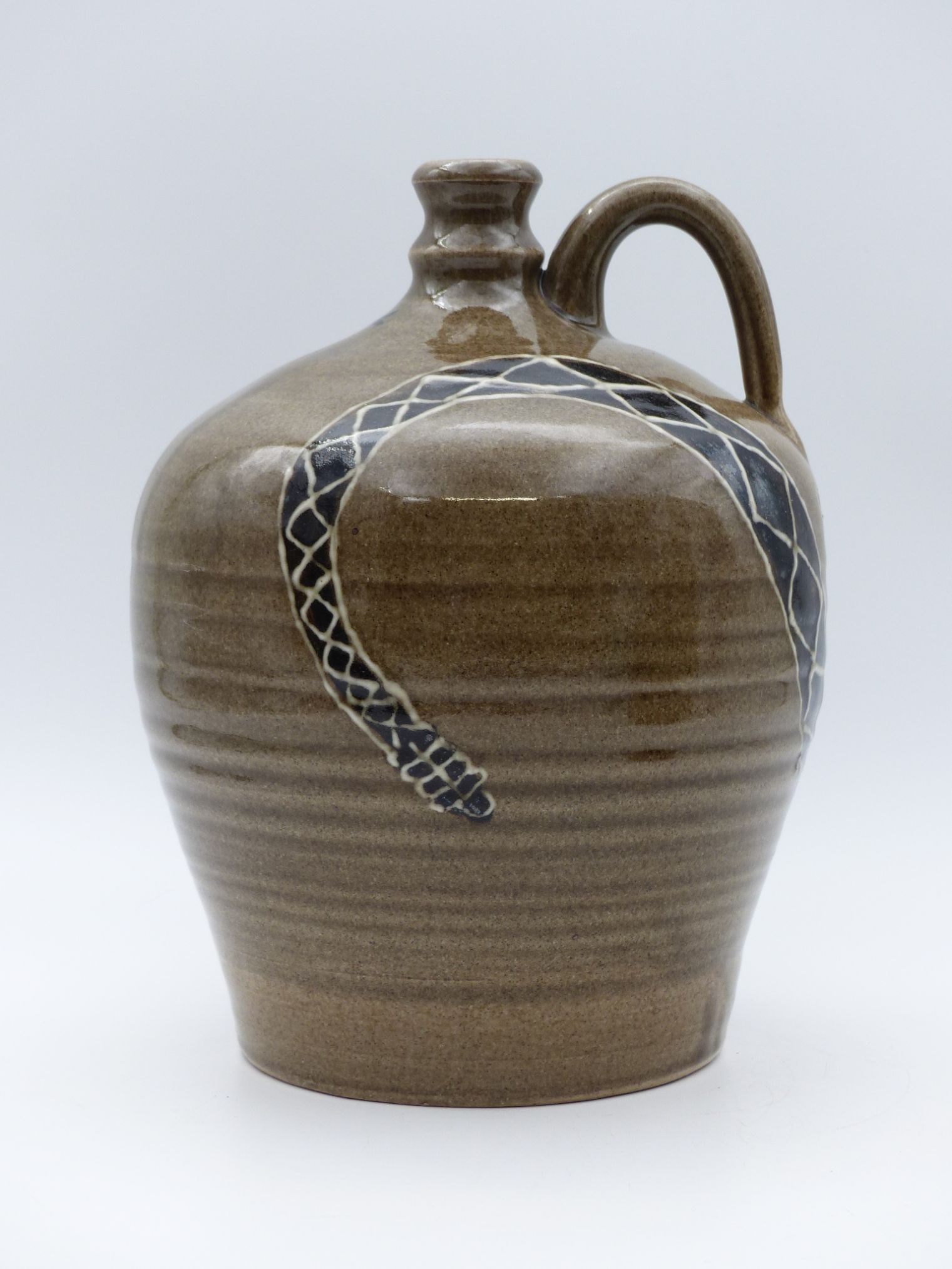"Michelle Bain Snake-Decorated Jug: This striking jug by Michelle Bain features an intricate snake decoration that elegantly wraps around its body, illustrating traditional craftsmanship and contemporary aesthetics. The piece is beautif
