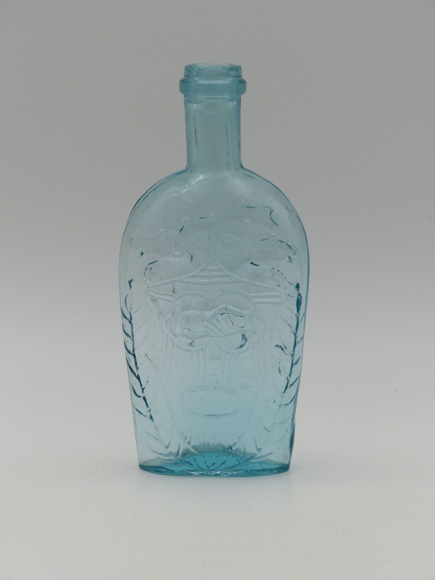 Small Union Flask: Clasping Hands Eagle (Mint): This Small Union Flask features a striking design that includes clasping hands and an eagle motif, characteristic of early American spirit flasks. Made of a vibrant blue glass, the flask exhibits intr