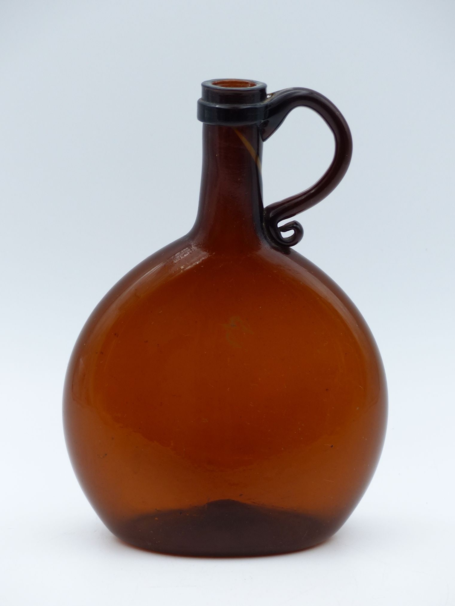Amber Chestnut Bottle (Excellent Condition): This exquisite Amber Chestnut Bottle exhibits a stunning, warm hue that highlights its vintage craftsmanship. The bottle boasts a gracefully contoured shape with a decorative handle, lending it an ele