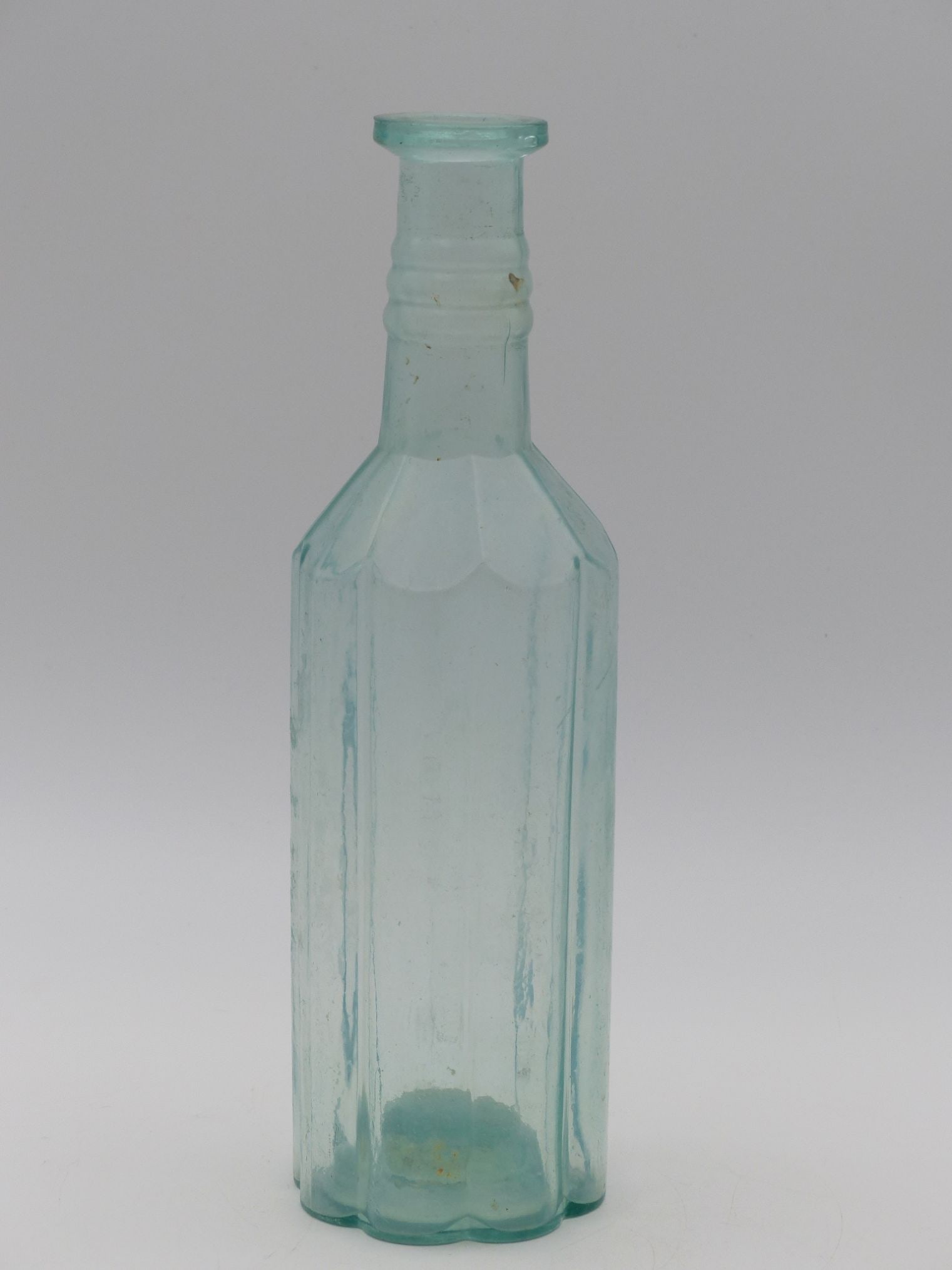 Aqua Flat Top Bottle (Likely Pickle Juice): This exquisite Aqua Flat Top Bottle, likely used for pickle juice, showcases a refined design characteristic of its era. The bottle features octagonal facets that reflect light beautifully, capturing 