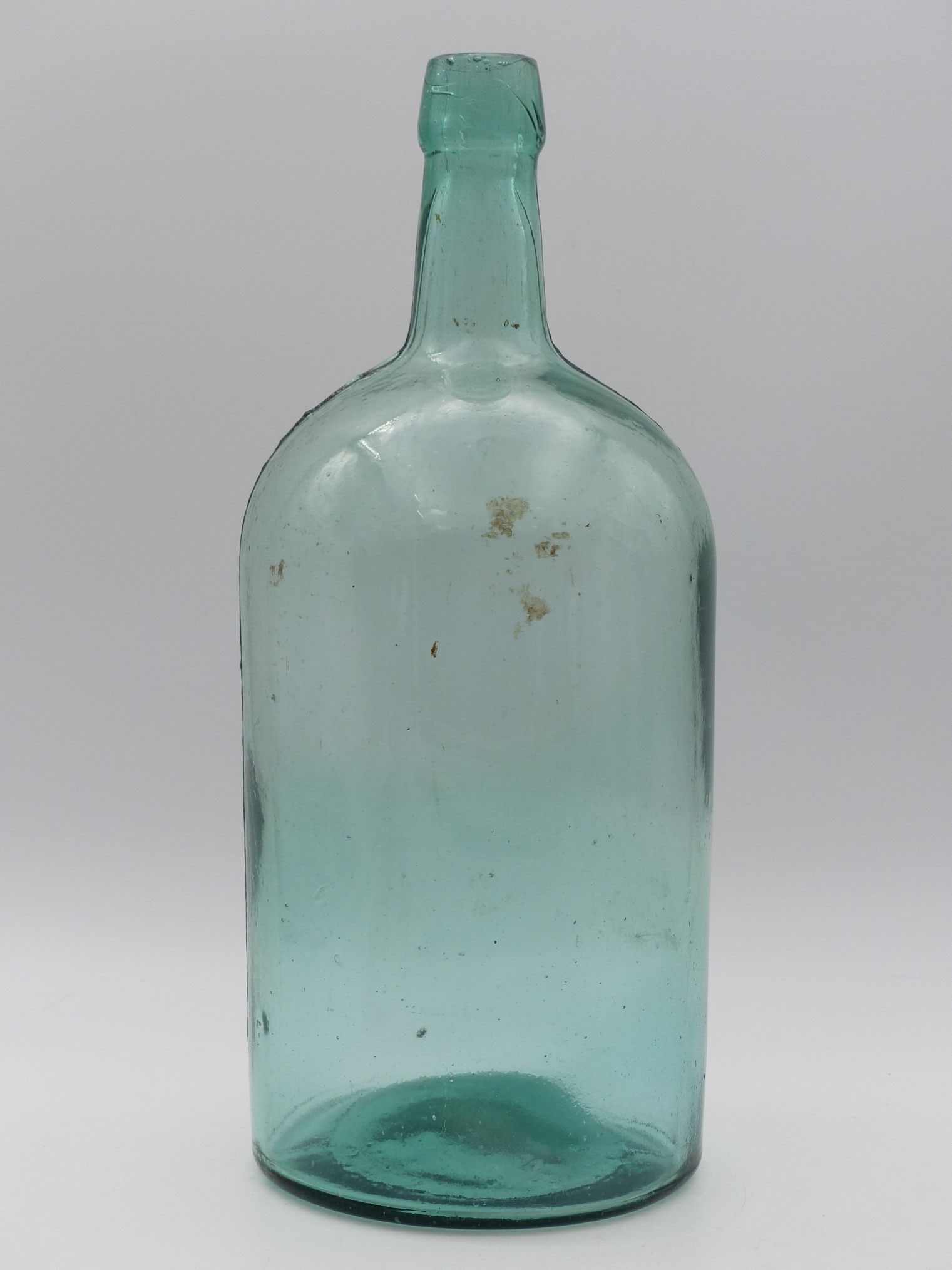 Aqua Demijohn (Great Condition): This Aqua Demijohn embodies the elegance of traditional craftsmanship with its gracefully elongated neck and rounded body, showcasing an impressive transparent aqua hue that elegantly refracts light.