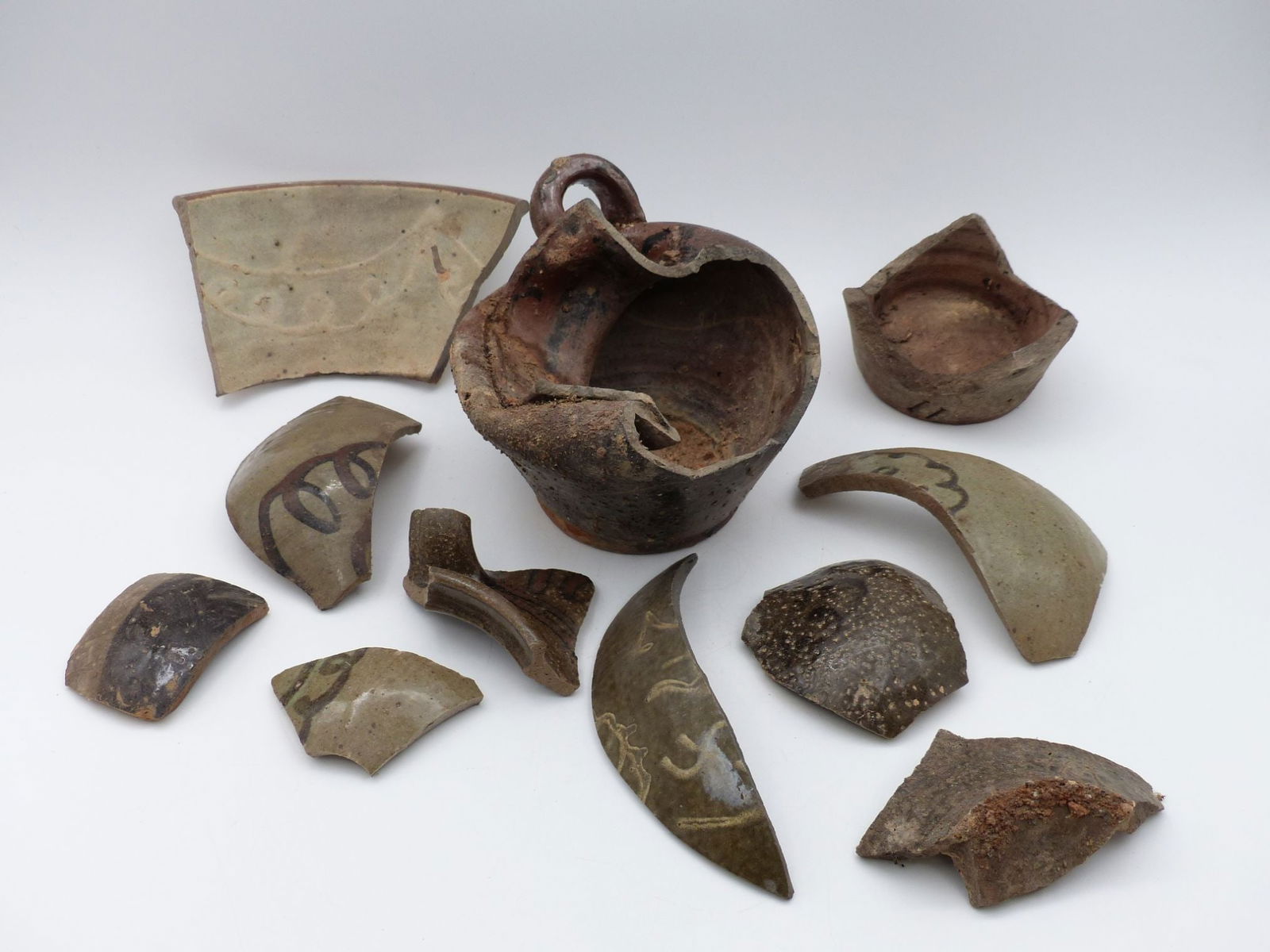 Trap & Chandler 1847 Dated Shard Collection: This exceptional lot features a collection of dated ceramic shards from Trap & Chandler, dating back to 1847. The assemblage showcases a variety of forms, including a notable handled vessel, alongside