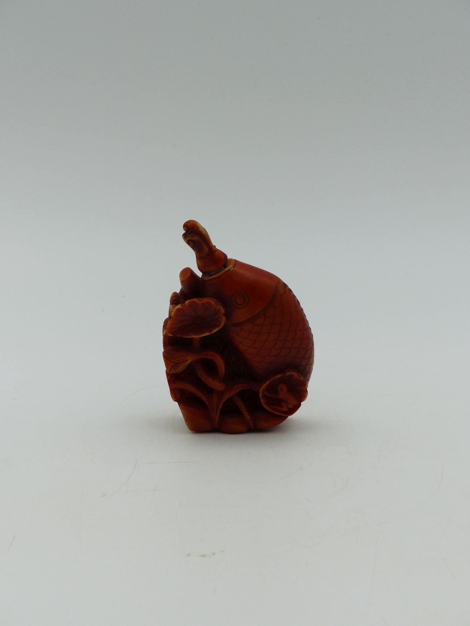 Asian Fish Bottle with Carved Bone Stopper: This exquisite Asian fish bottle, meticulously crafted from a vibrant red material, features a beautifully carved bone stopper shaped like a fish. The bottle is adorned with intricate detailing showca