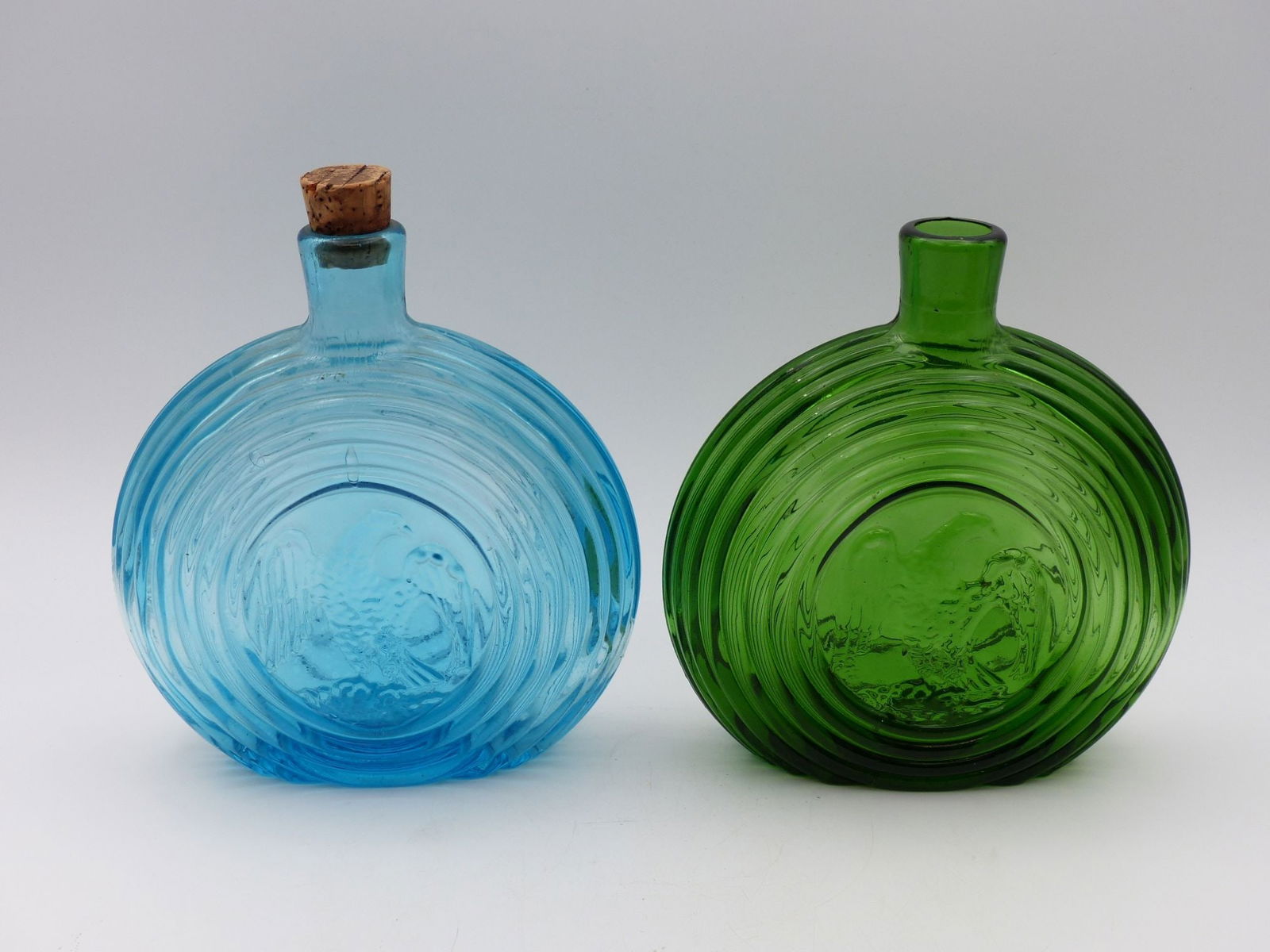 Round Eagle & Ball Flask Pair: This exquisite pair of Round Eagle and Ball flasks exemplifies fine craftsmanship and decorative art from the early 19th century. The flasks feature a prominent embossed eagle design set against a bac