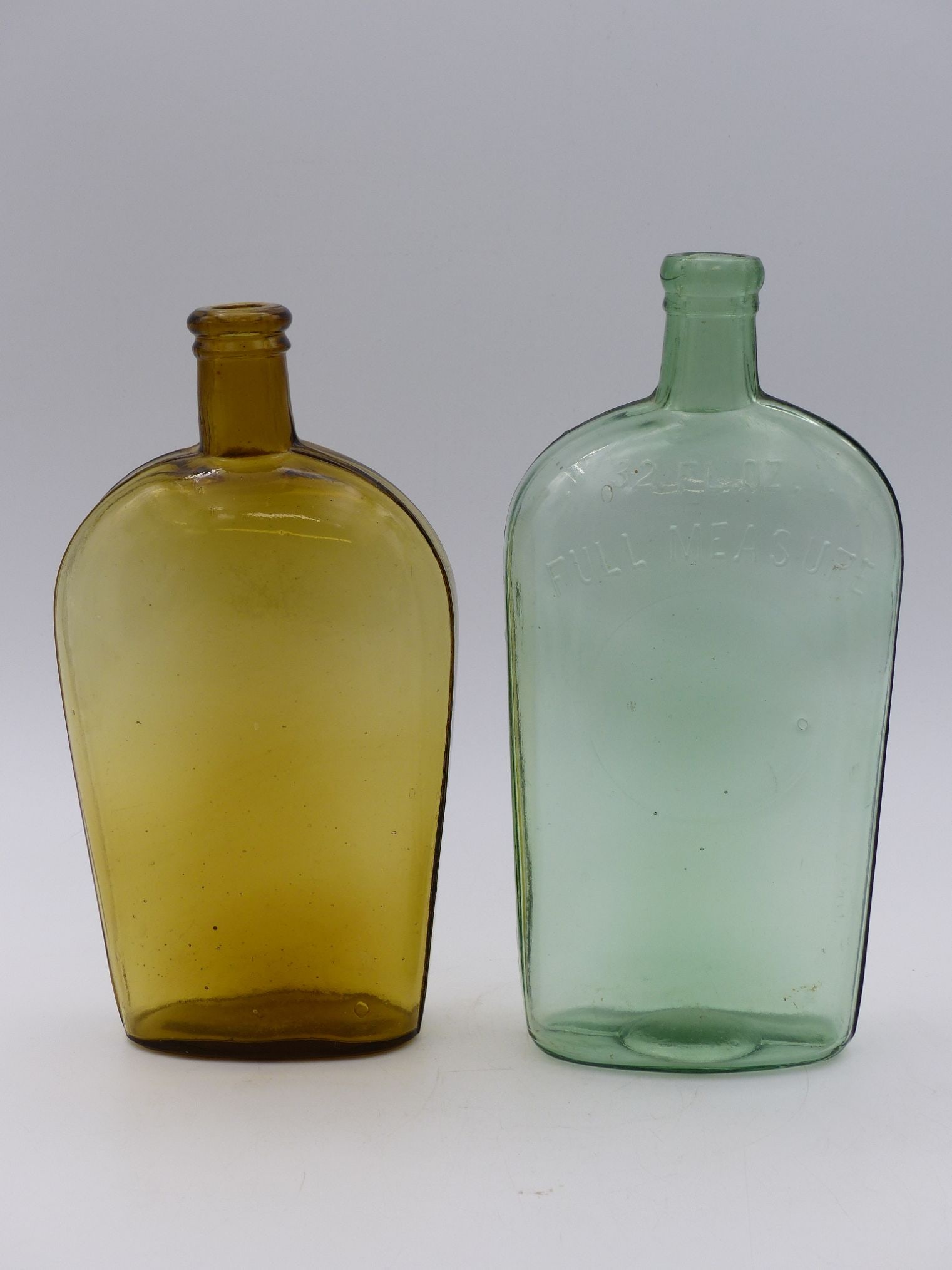 Horse-Shaped Flask Pair: Aqua & Green: This exquisite pair of horse-shaped flasks showcases a captivating interplay of colored glass, with one flaunting a rich amber hue and the other a tranquil aqua green. The unique geometric design feat