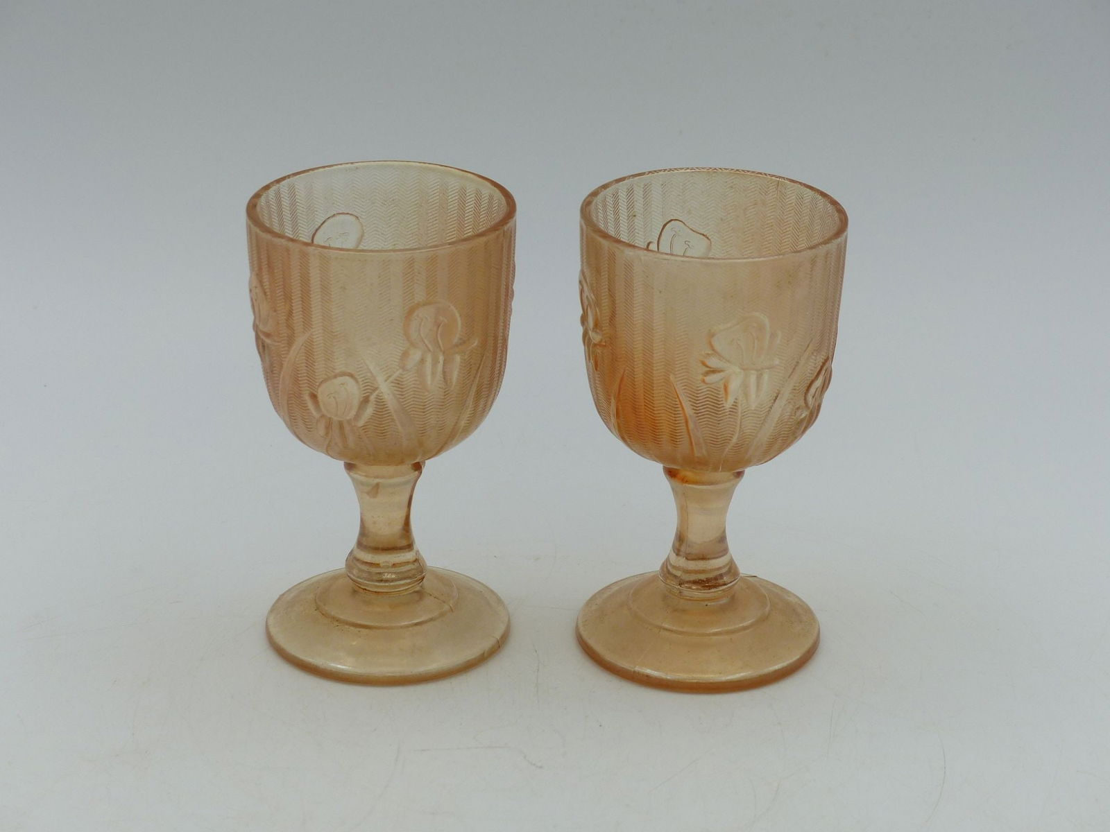 Iris & Herringbone Cordial Pair (Mint): This exquisite pair of Iris & Herringbone cordial glasses showcases delicate floral motifs of irises against a background of elegantly patterned herringbone design, rendered in a soft peach hue. The c