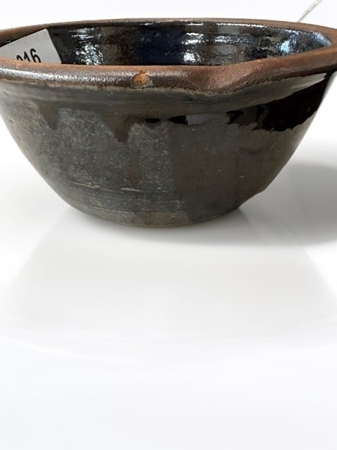 Rustic Dark Glazed Ceramic Mixing Bowl: A charming, hand-thrown ceramic bowl featuring a deep, dark brown to black glaze on the interior and a partially glazed exterior. The piece showcases a thick, sturdy rim and a warm, earthy terracotta 