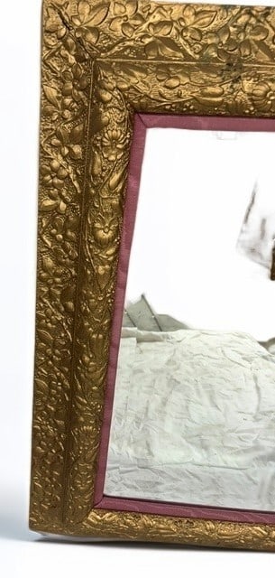 Giltwood Wall Mirror with Floral Relief Carving: This elegant wall mirror features a heavy giltwood frame intricately decorated with continuous floral and foliate relief carvings. The mirror plate is accented by a subtle, soft rose-toned fabric inne