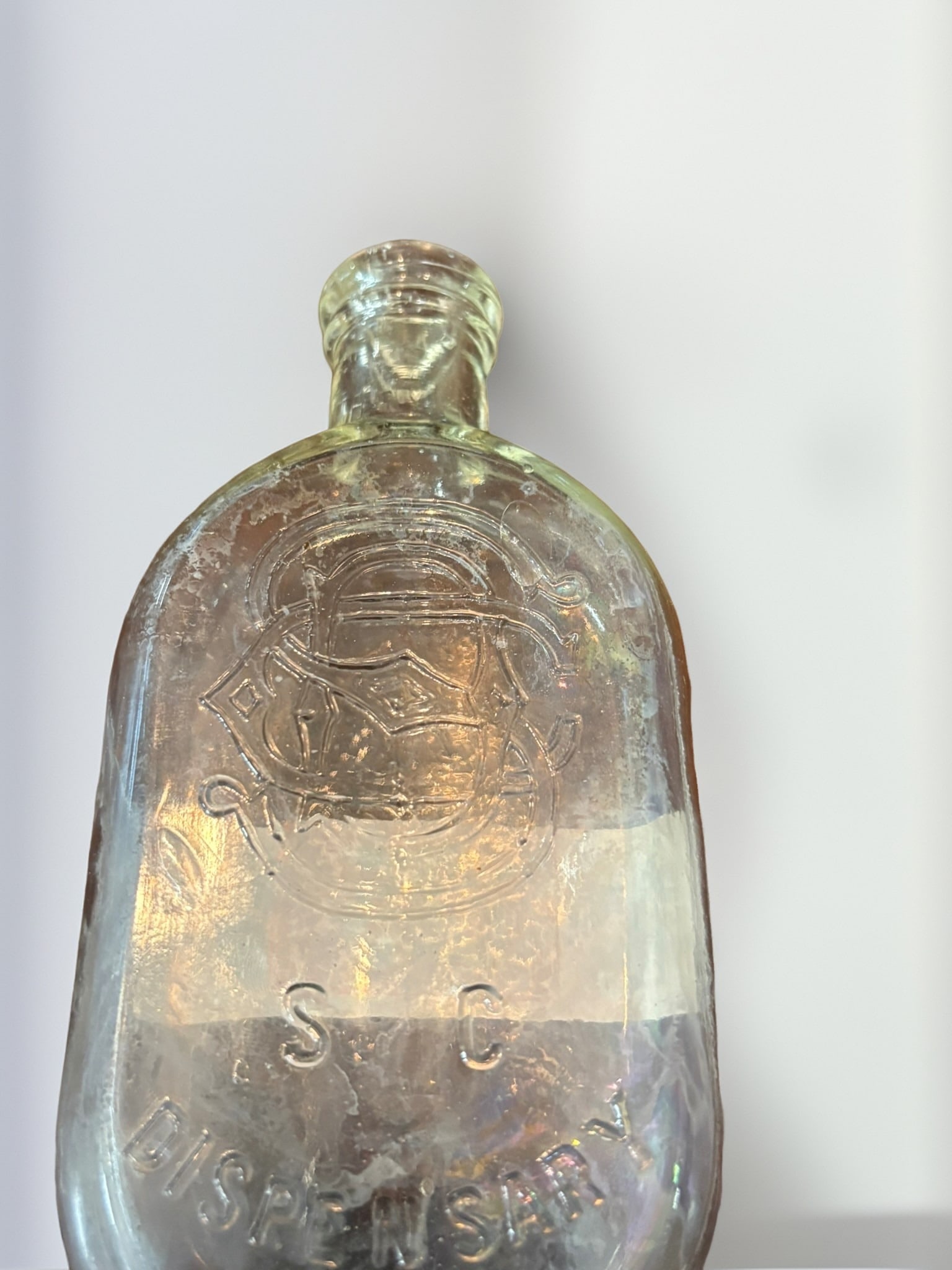 South Carolina Dispensary Clear Glass Flask: This antique clear glass flask is a notable piece of South Carolina state history, featuring the distinctive palmetto tree and crescent emblem of the South Carolina Dispensary. The bottle bears molded