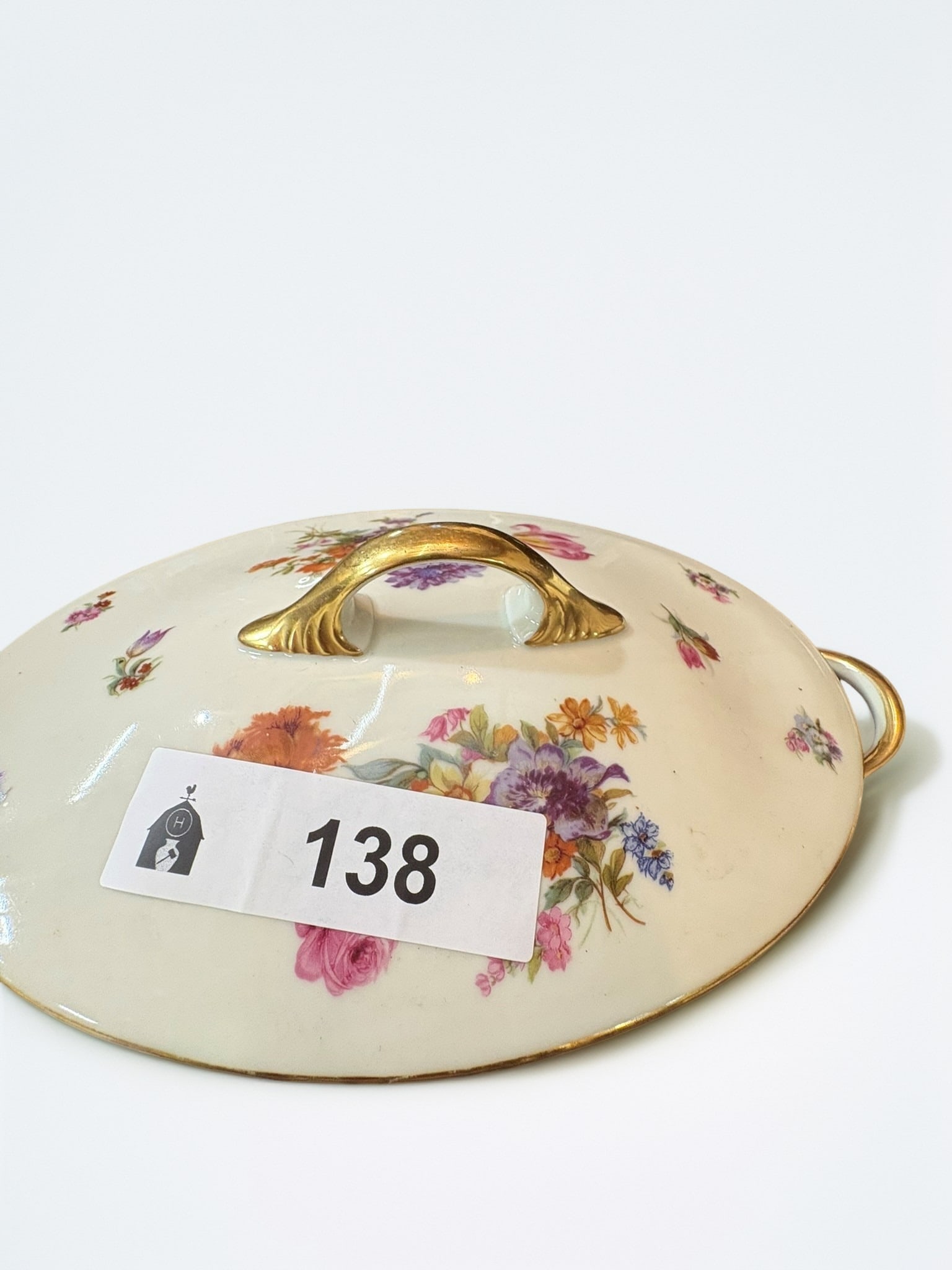 Vintage Porcelain Floral Serving Tureen: This elegant oval serving tureen features a delicate floral pattern against a cream-colored porcelain body, accented with gold-toned trim and handles. Its classic silhouette makes it a refined choice