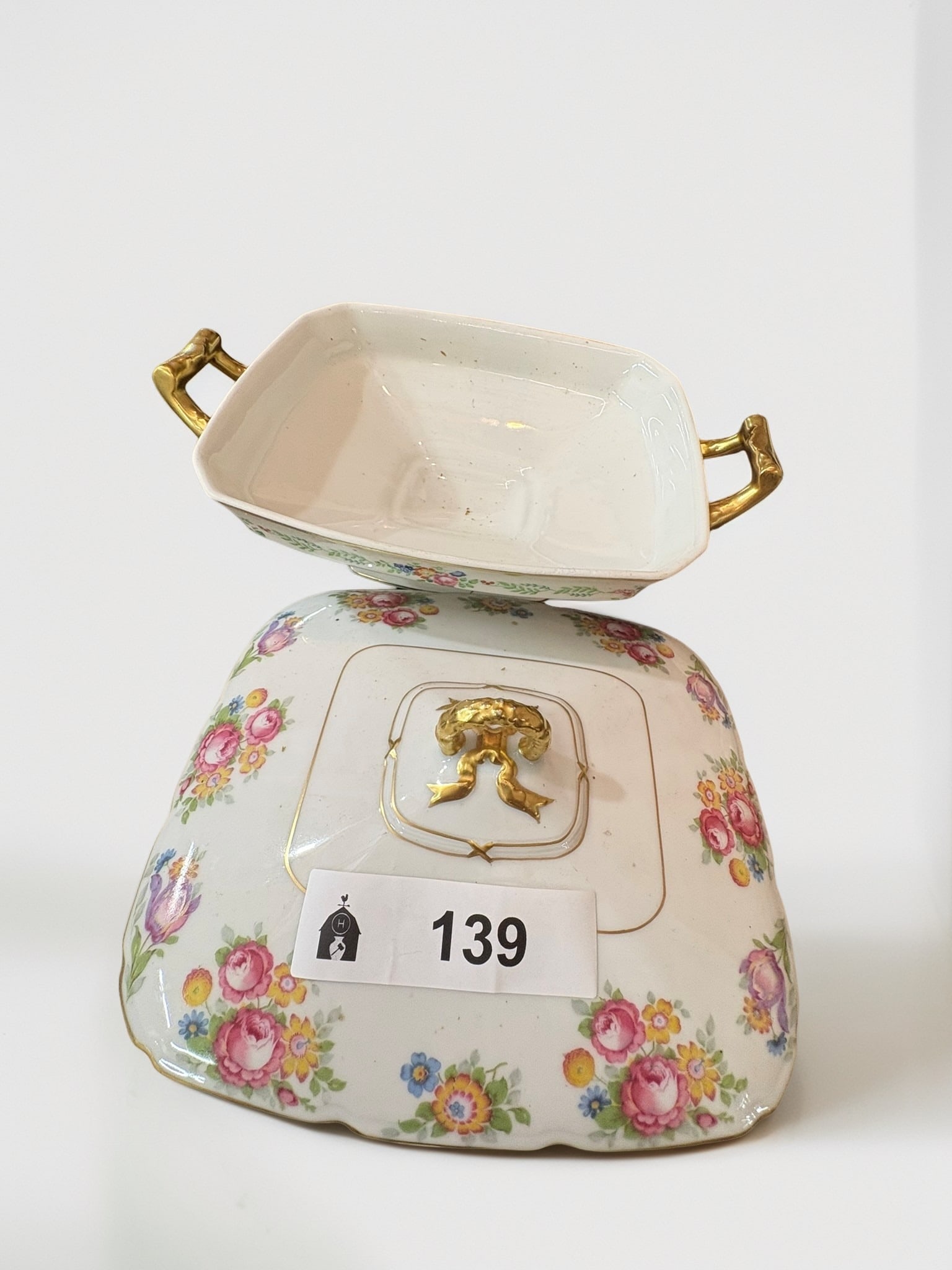 T&V Limoges Porcelain Vegetable Tureen with Floral Motif: This elegant French Limoges porcelain vegetable tureen, marked by T&V (Tressemann & Vogt), features a delicate hand-painted floral design over a white glaze. The piece is accented with gilded handle f