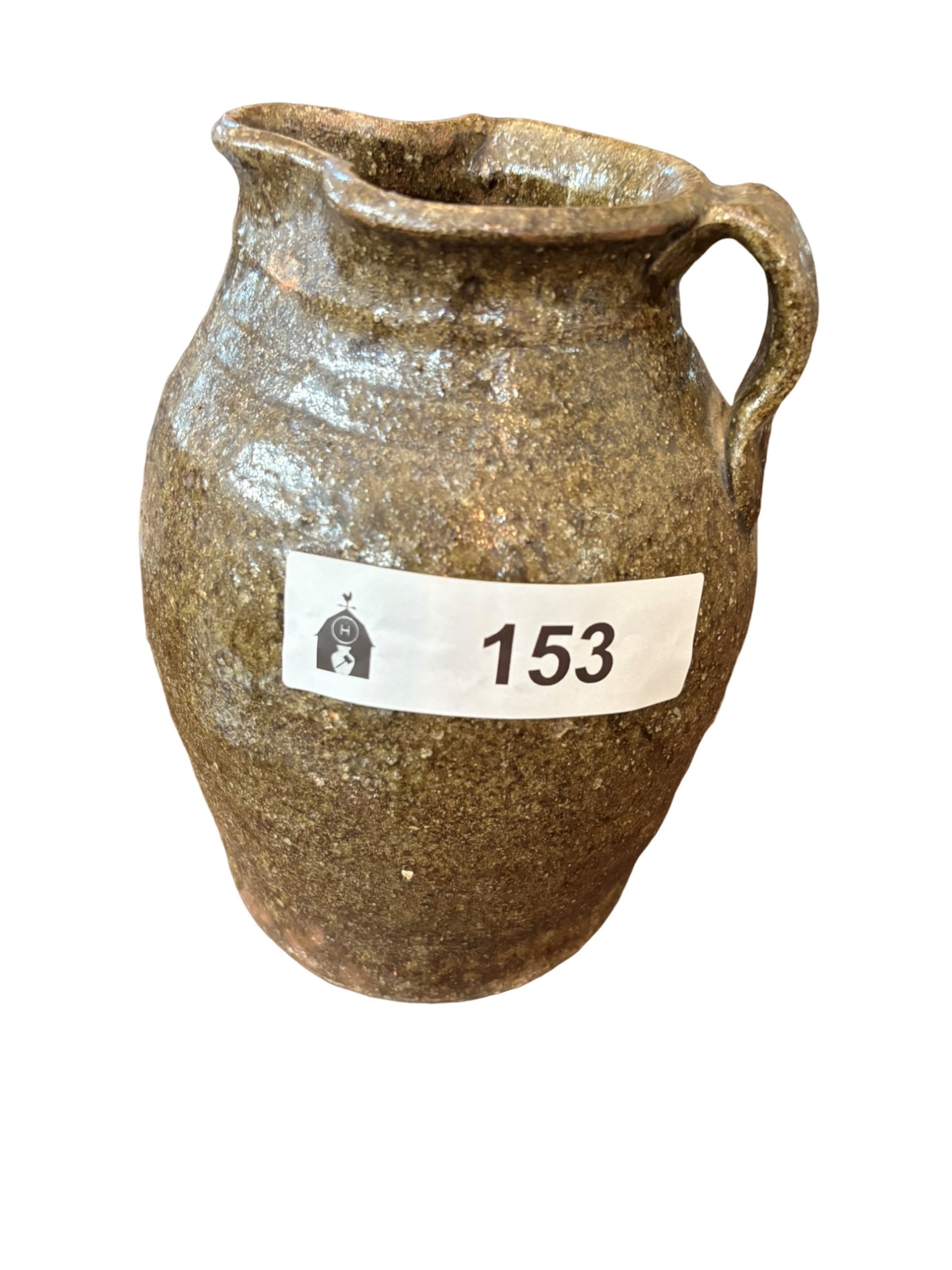 Rustic Earth-Toned Earthenware Pitcher: This charming, rustic earthenware pitcher features a textured, earth-toned glaze with characteristic pitting and variation indicative of traditional folk pottery methods. The vessel showcases a