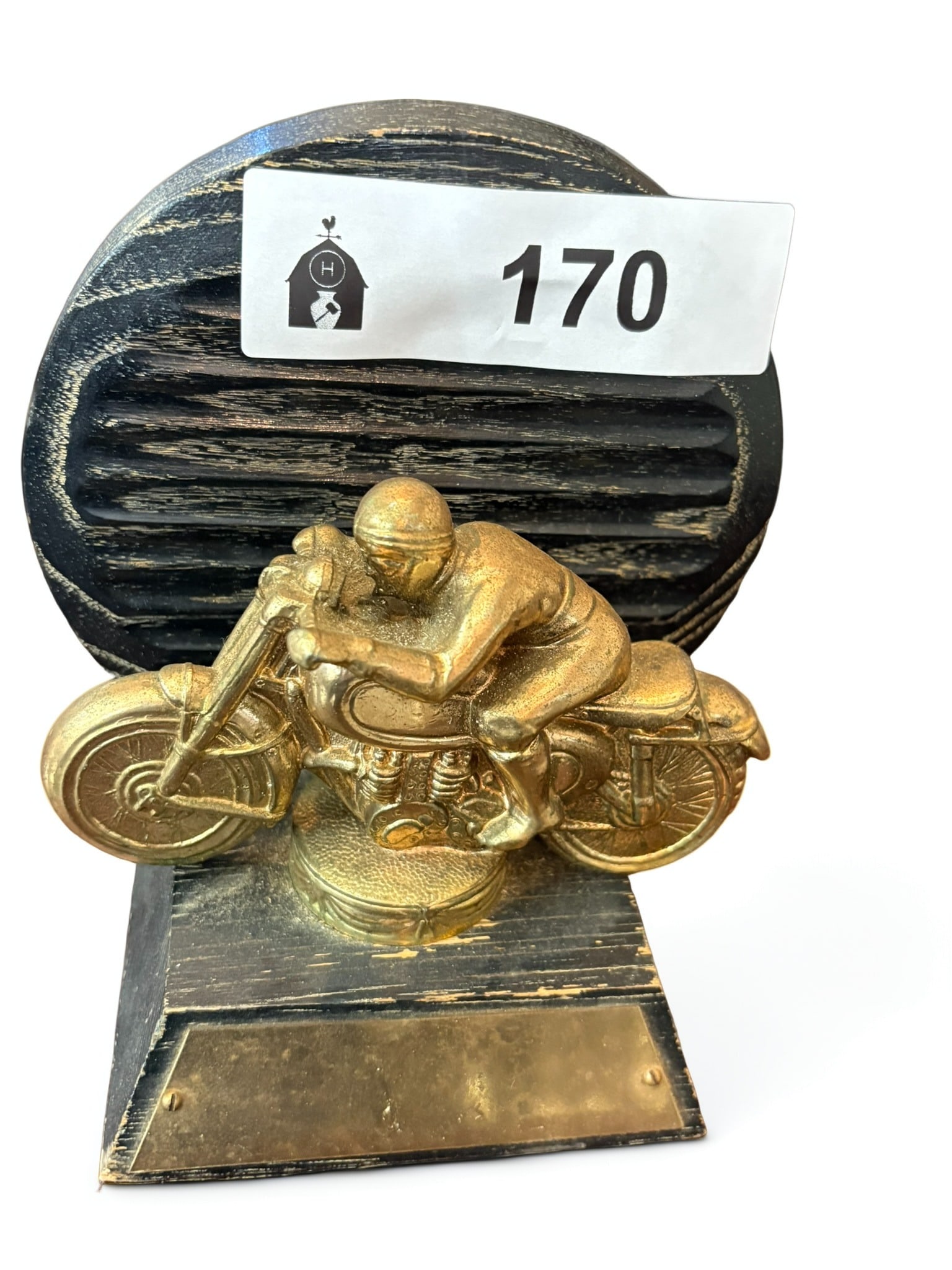 Vintage Motorcycle Racer Trophy Sculpture: This vintage trophy features a detailed gold-toned metal figure of a motorcycle racer in a classic tuck position. The sculpture is mounted on a decorative, circular gold base, which itself sits atop a