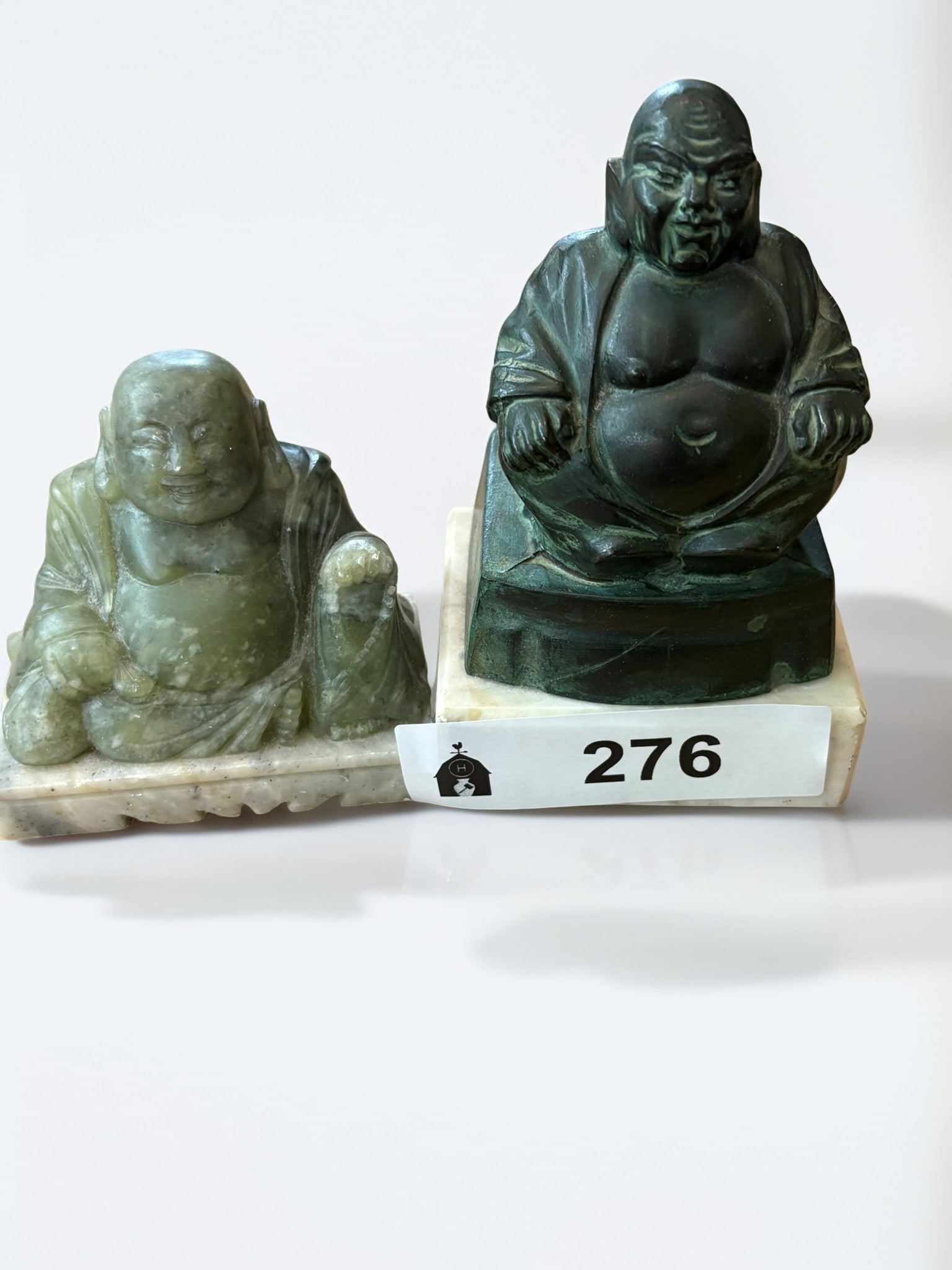 Pair of Miniature Budai Figural Sculptures: This lot features a pair of miniature Budai or 'Laughing Buddha' figures, each presenting a distinct material and artistic style. One figure is carved from a mottled green stone, possibly nephrite jad