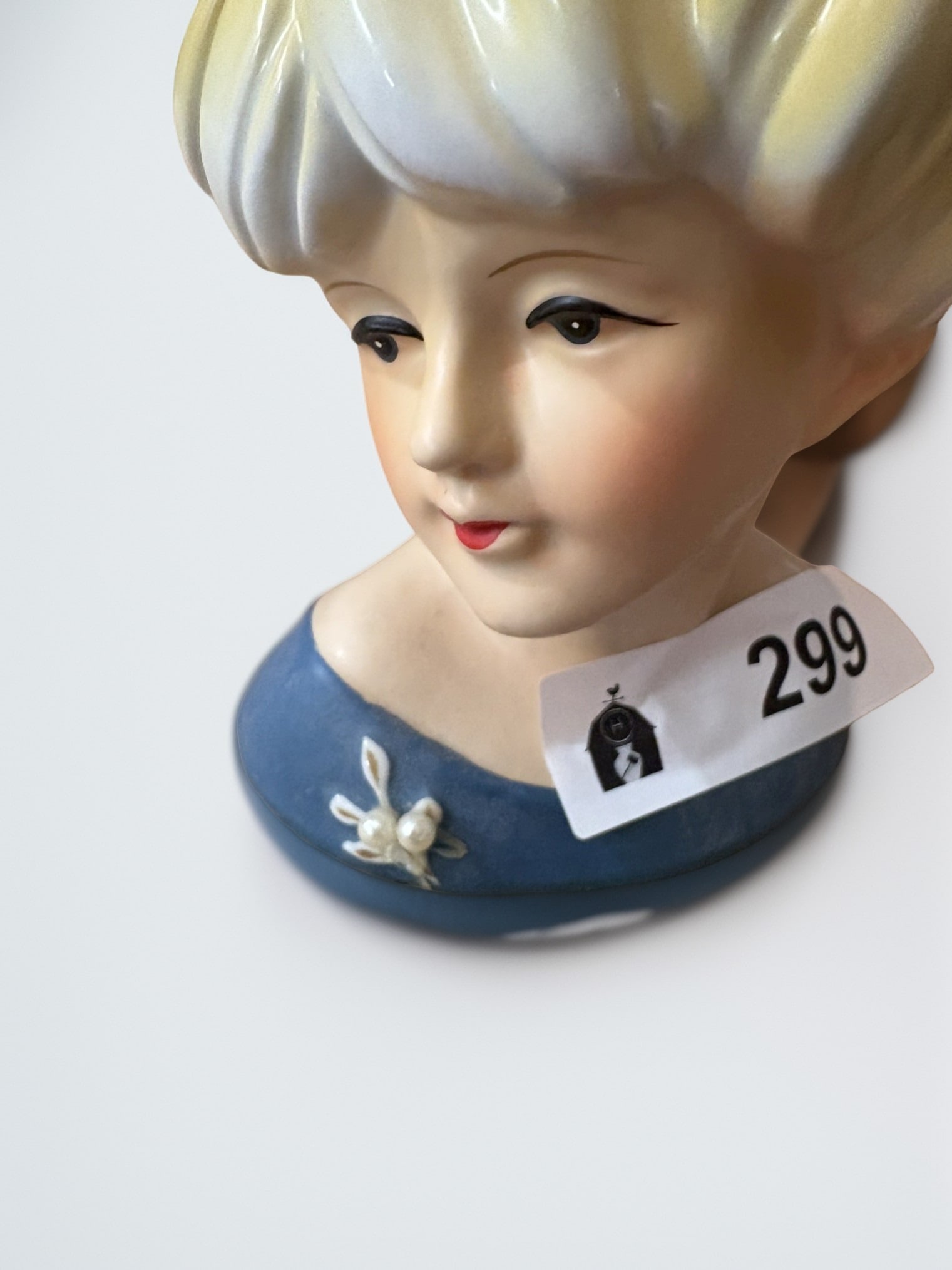 Vintage Hand-Painted Nippon Porcelain Figural Head Vase: This charming vintage head vase features a stylized woman with a vibrant yellow sculpted coiffure and a blue bodice accented by a white floral brooch. Expertly crafted in porcelain, the piece bears th