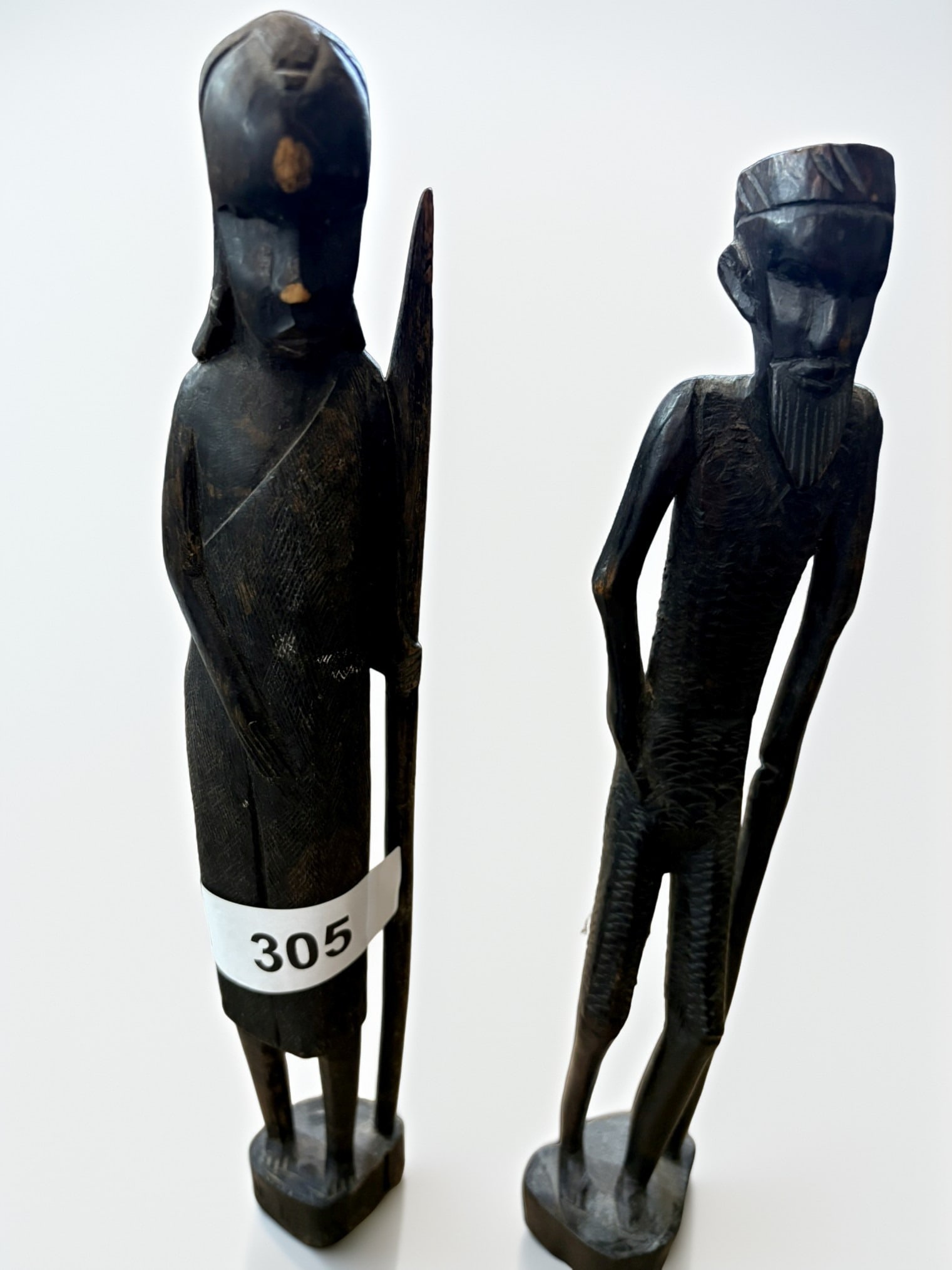 Pair of African Hand-Carved Ebony Wood Figurines: This pair of exquisite hand-carved ebony wood figures depicts traditional male and female forms, likely of East African origin. The artisan has utilized the deep, rich natural tones of the ebony to ac