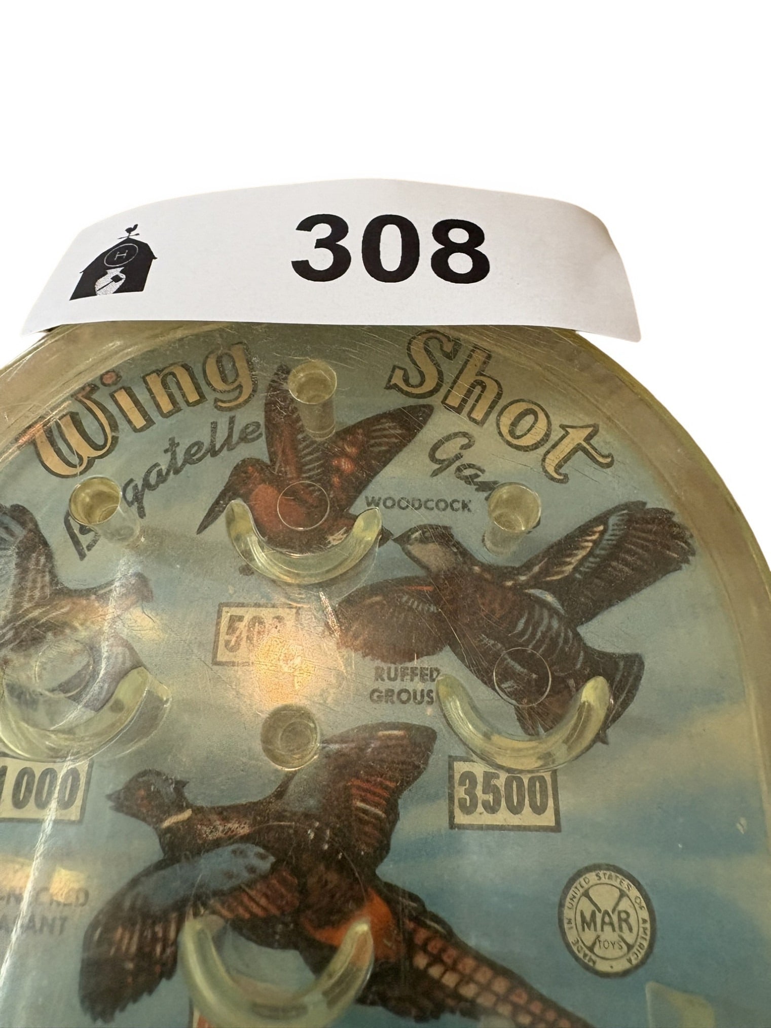 Vintage Marx 'Wing Shot' Bagatelle Game: A charming vintage 'Wing Shot' bagatelle toy by Marx, featuring a hunting-themed lithographed playing board under a clear plastic cover. The game includes various point-scoring pockets marked with gam