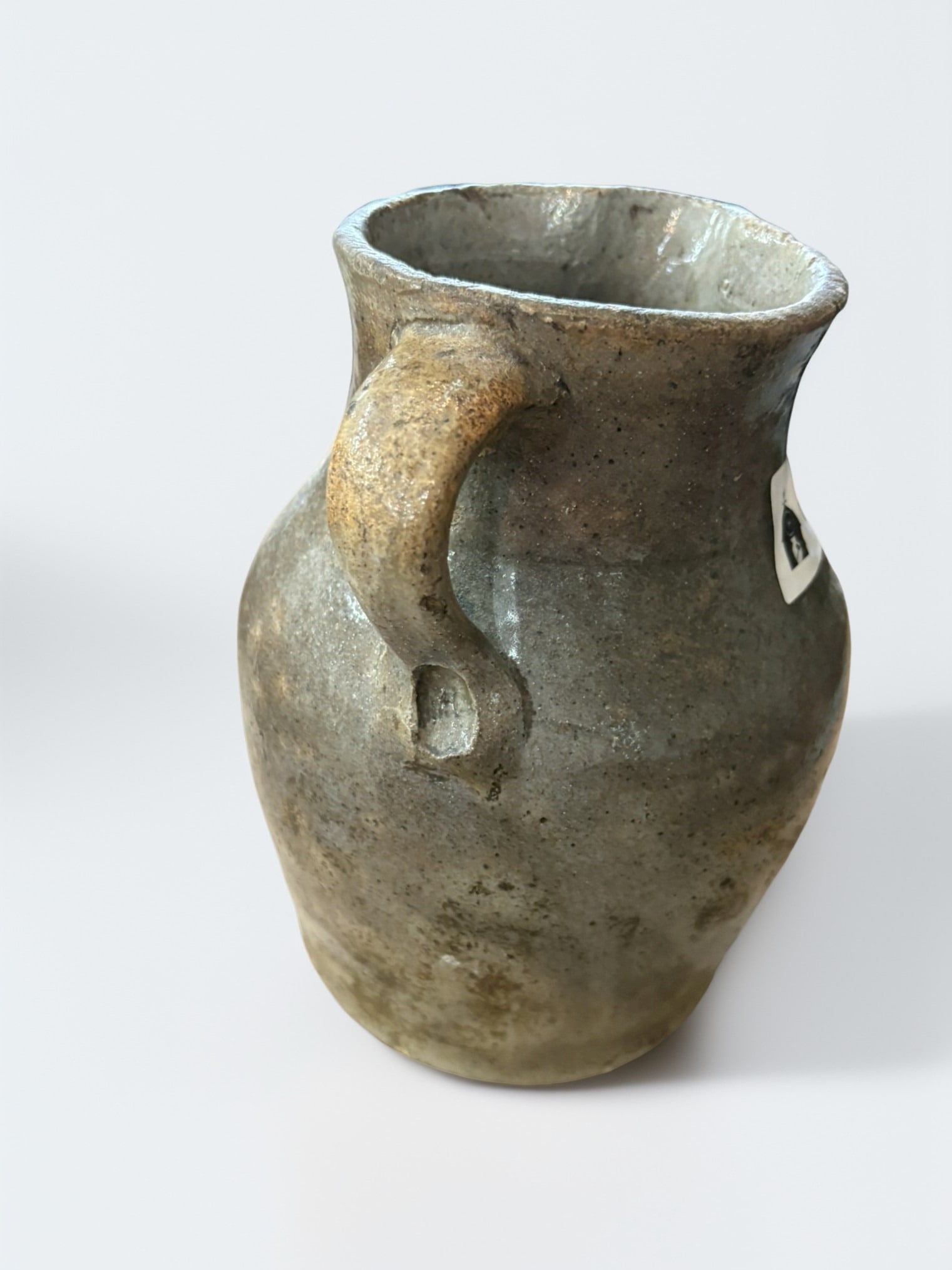 19th Century Southern Alkaline Glazed Stoneware Pitcher: An authentic 19th-century American Southern stoneware pitcher, featuring the characteristic mottled, earth-toned alkaline glaze. The form displays traditional hand-thrown construction, with a robust b