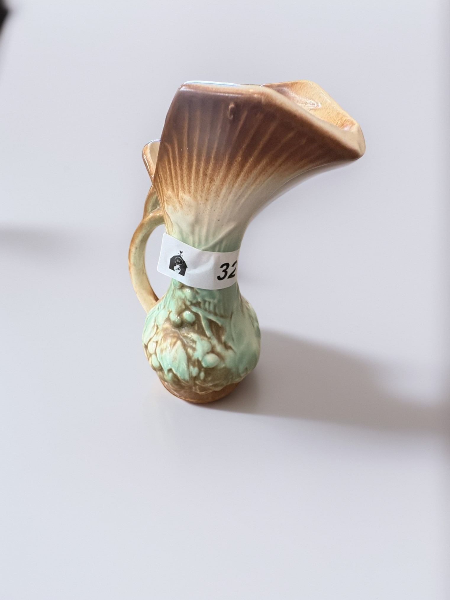 Vintage Ceramic Shell and Leaf Pitcher: This charming vintage ceramic pitcher features a unique shell-inspired form with delicate leaf detailing at the base. It is finished in a beautiful gradient glaze, transitioning from a warm tan at the