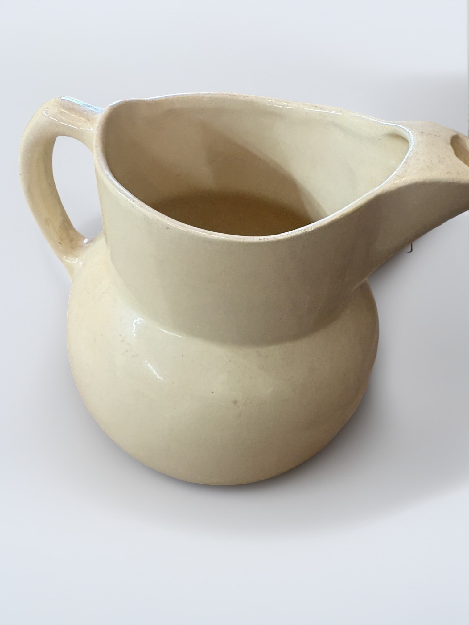 Vintage Watt Pottery Tulip Pattern Creamware Pitcher: This charming vintage pitcher is a classic example of American pottery, produced by the renowned Watt Pottery Company. The piece features a soft, creamy off-white glaze adorned with hand-painted styli